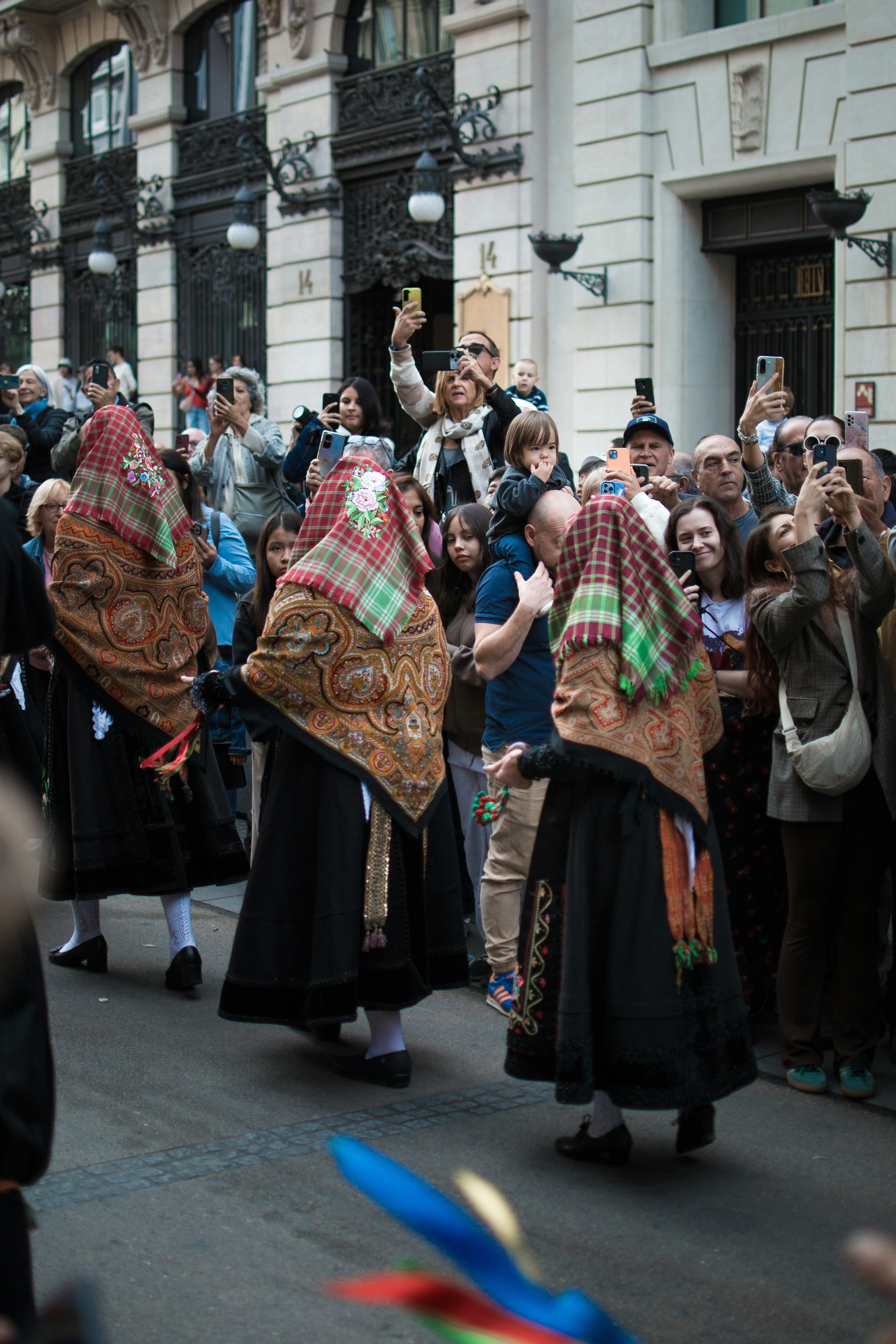 People in traditional costumes marching in a street parade.