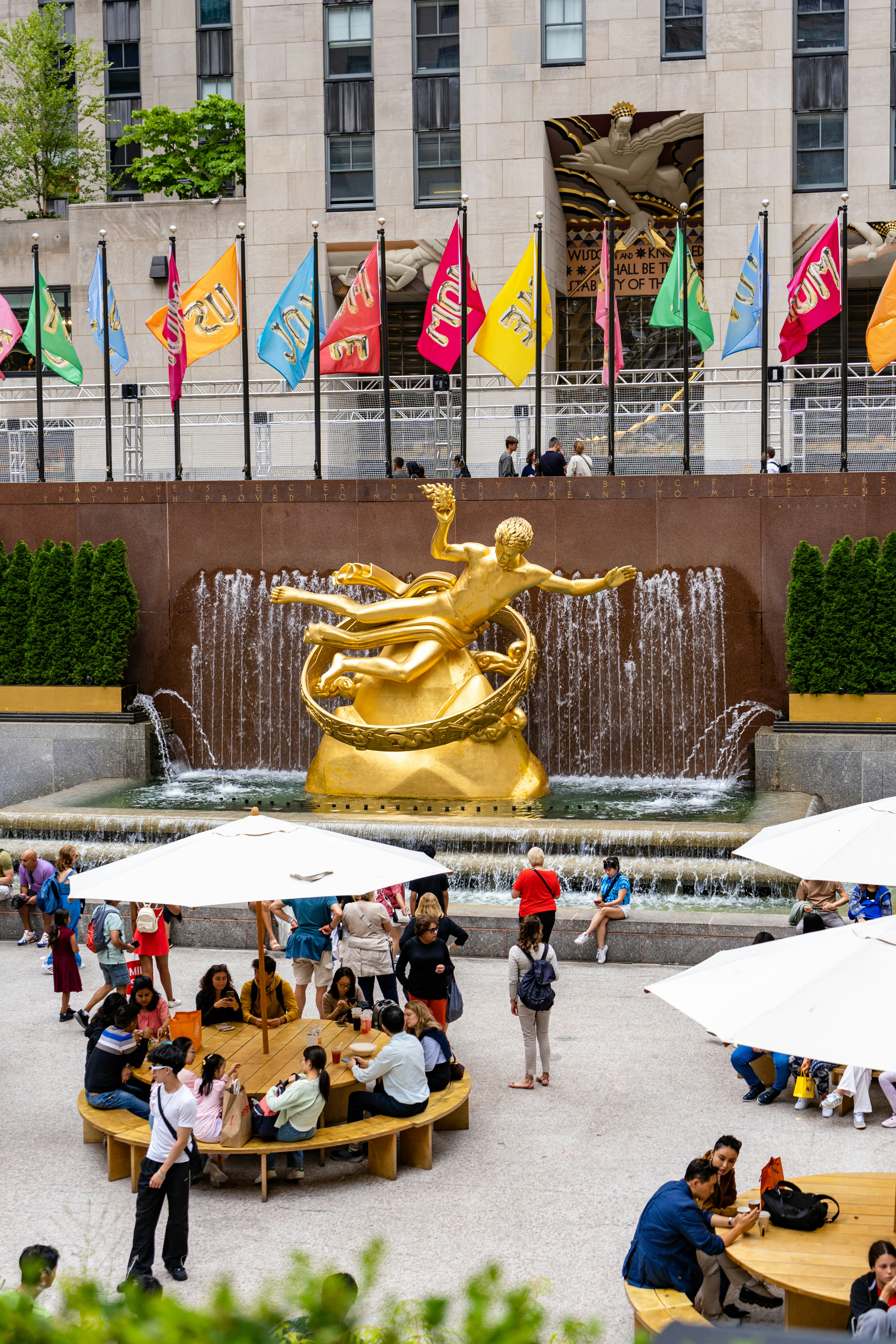 Estatua dorada con fuente y gente en la plaza