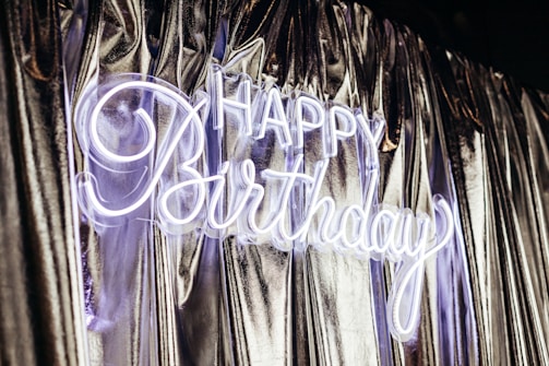 Happy birthday neon sign on shiny curtains