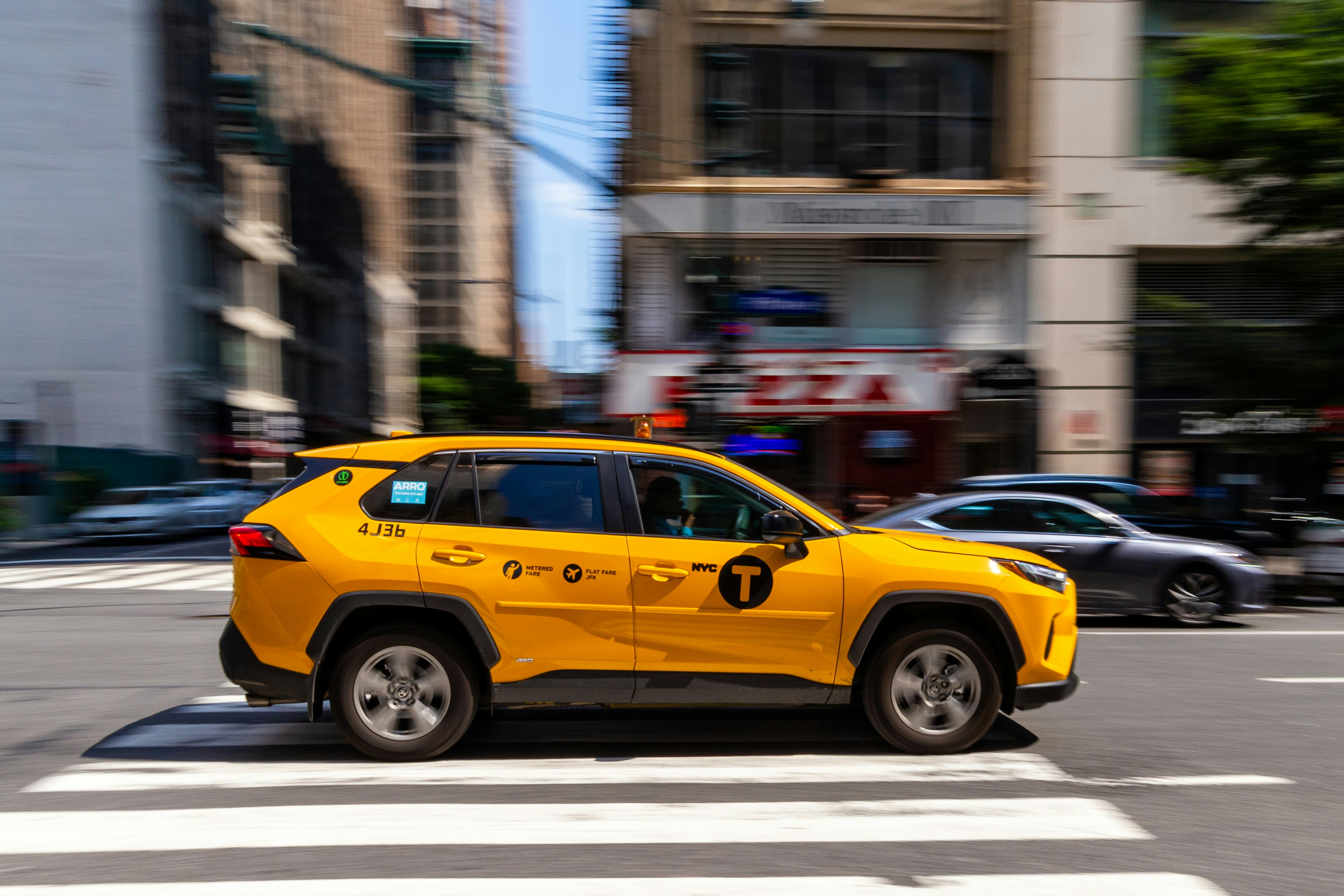 Táxi amarelo dirigindo por uma rua da cidade.