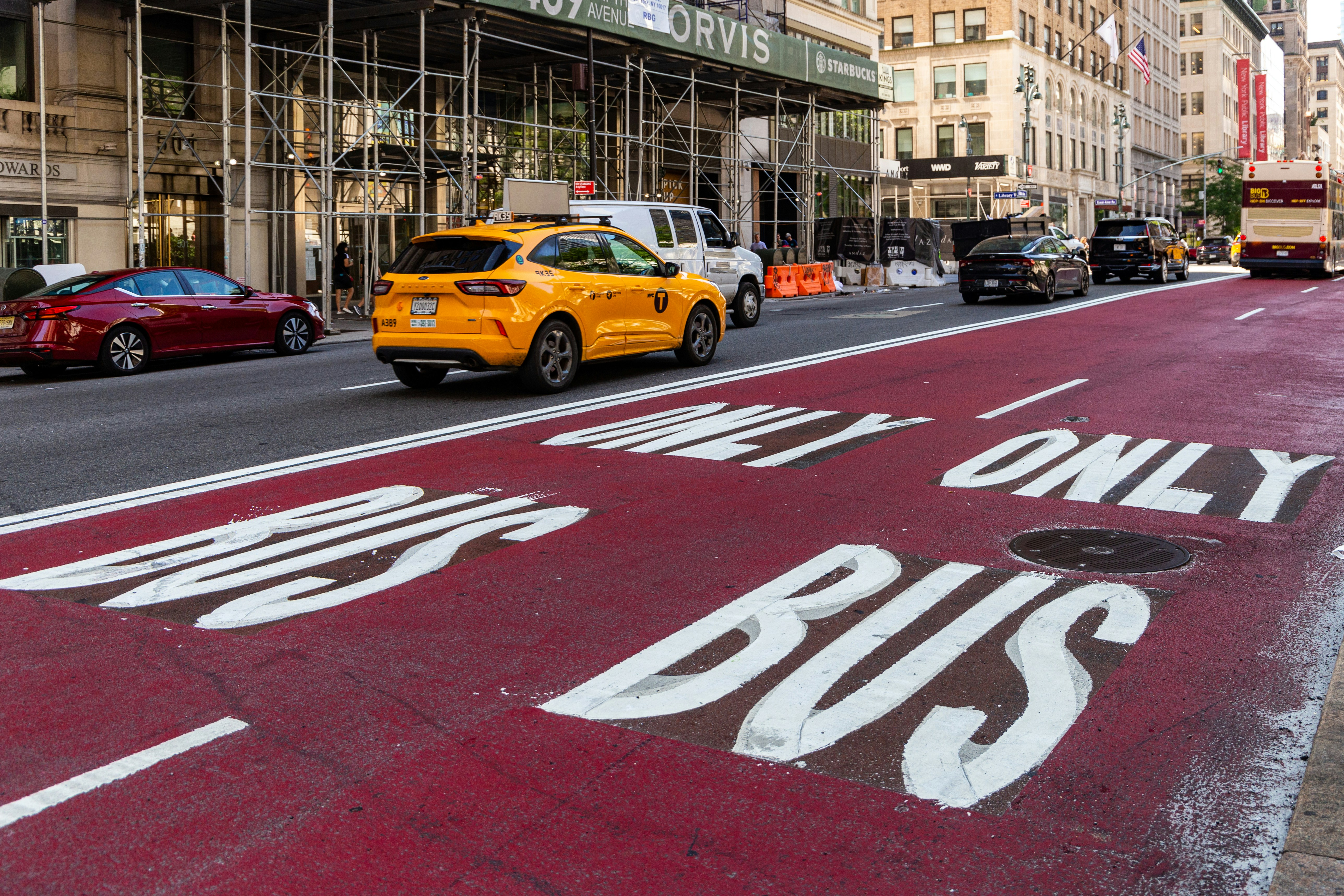Yellow taxi drives in a bus-only lane.