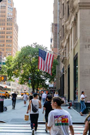 People walk on a street with an american flag.