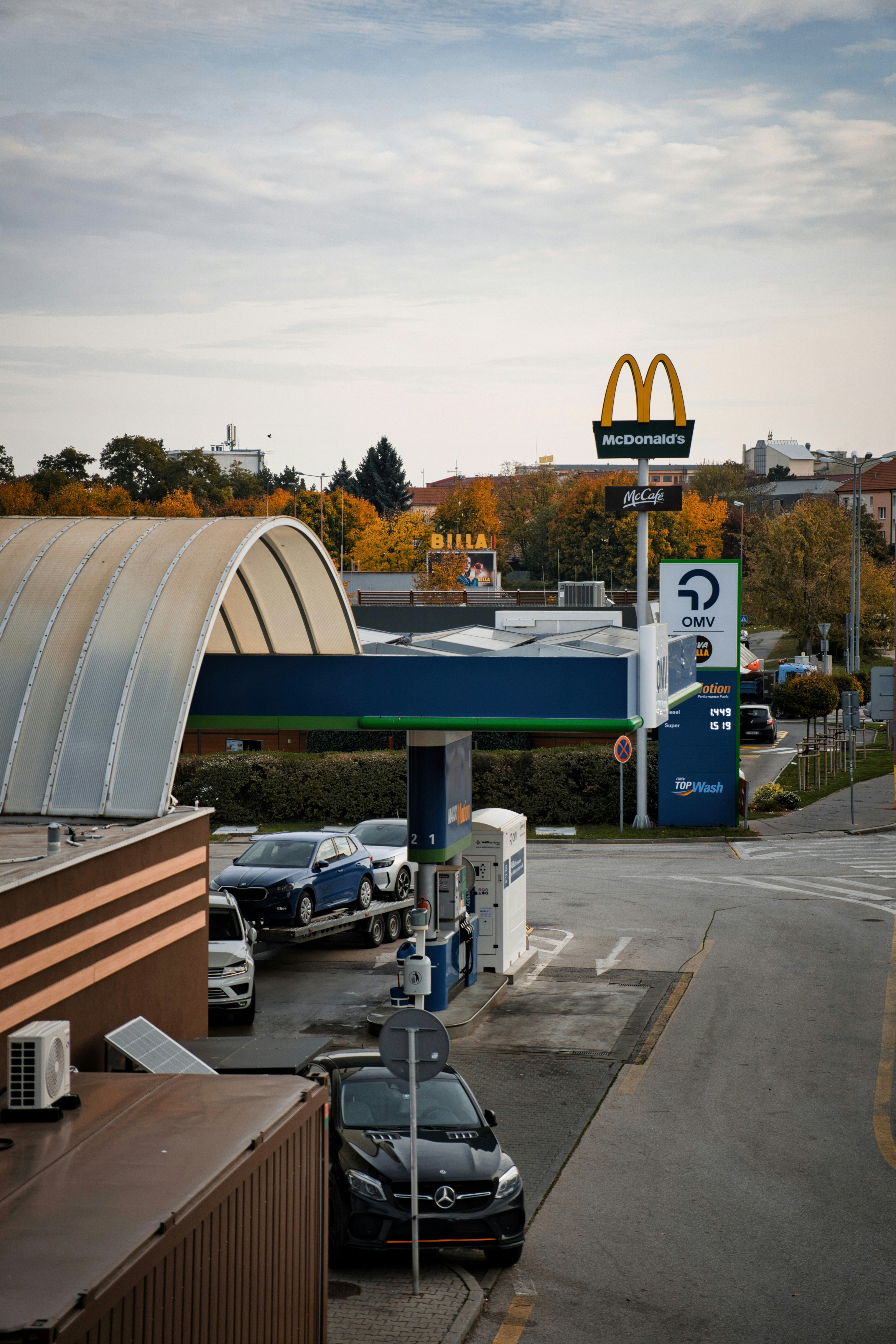 Cars at a gas station with mcdonald's sign.