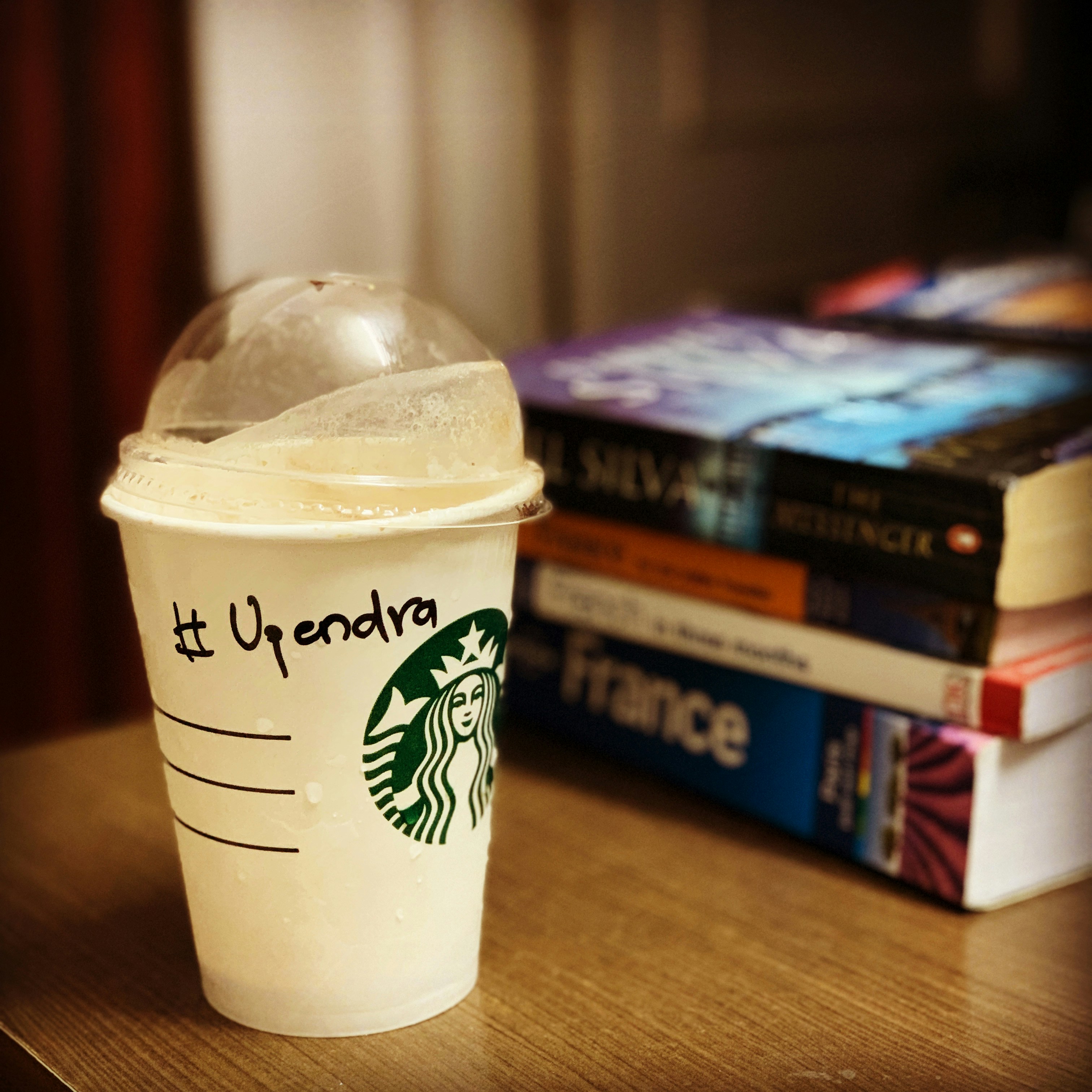 Tasse Starbucks avec nom et pile de livres