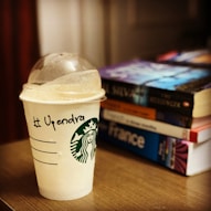 Starbucks cup with name and stack of books
