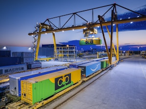 Gantry crane loading containers onto a train at dusk.
