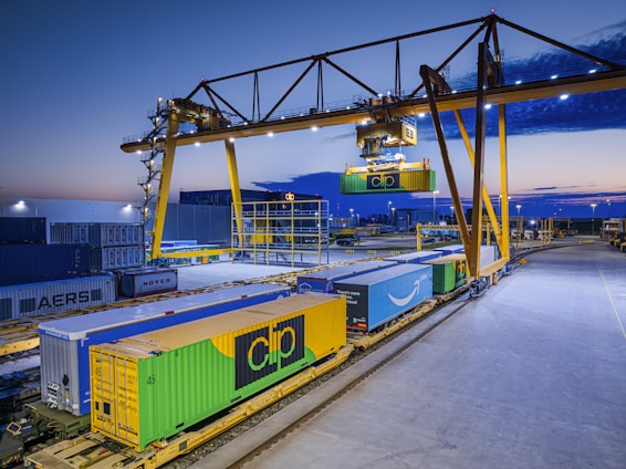 Gantry crane loading containers onto a train at dusk.