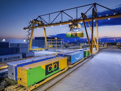 Gantry crane loading containers onto a train at dusk.