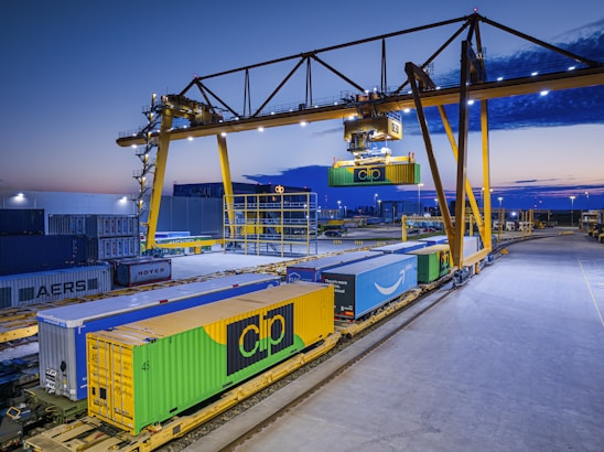 Gantry crane loading containers onto a train at dusk.