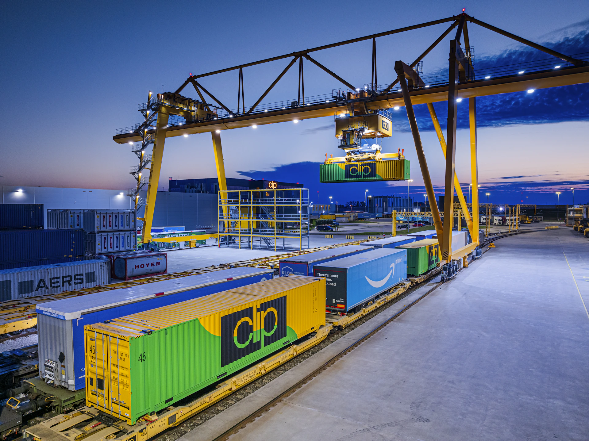 Gantry crane loading containers onto a train at dusk.