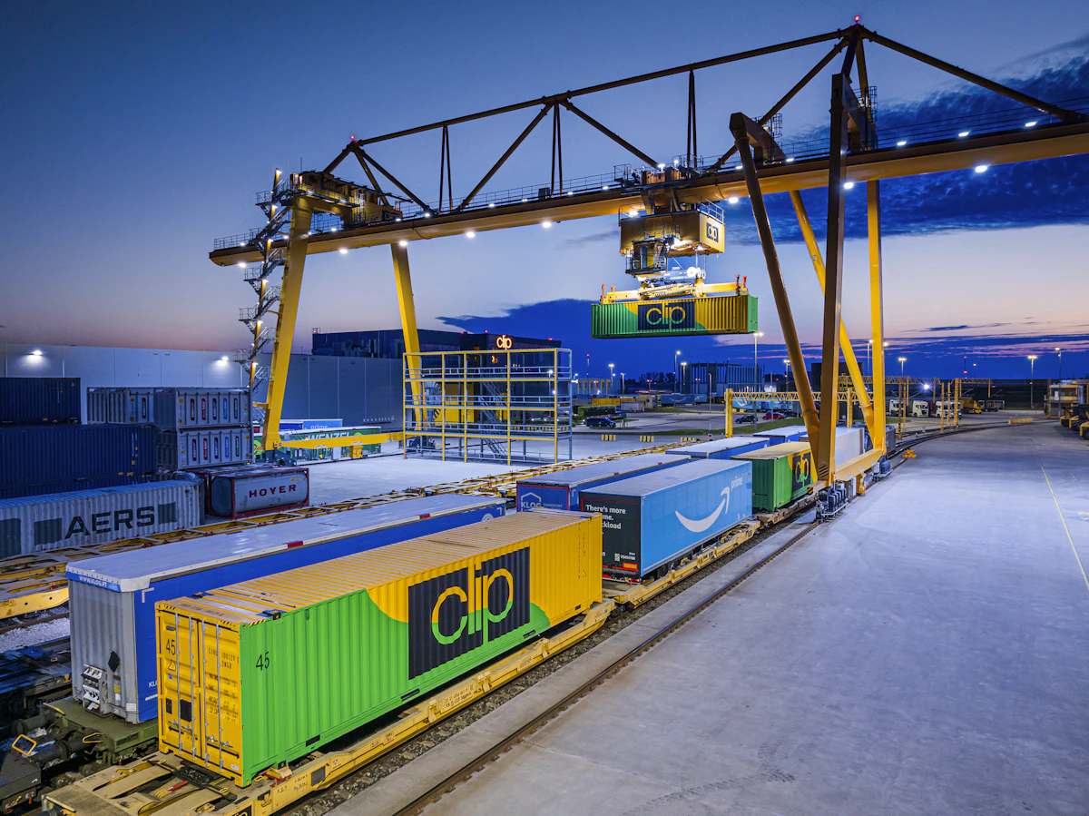 Gantry crane transferring intermodal containers onto a freight train at an intermodal ramp at dusk