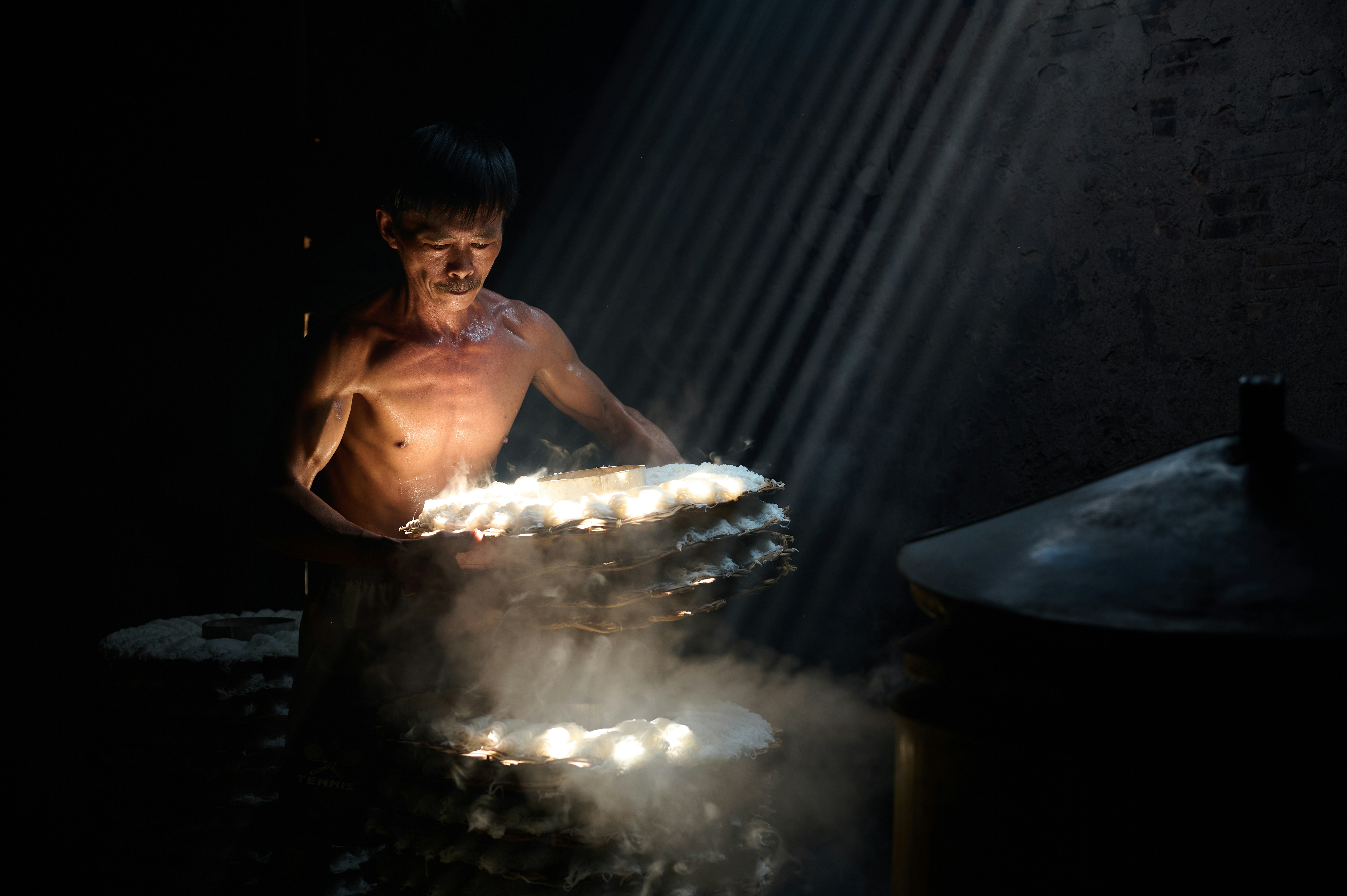 Man cooking food in a dark, rustic kitchen.