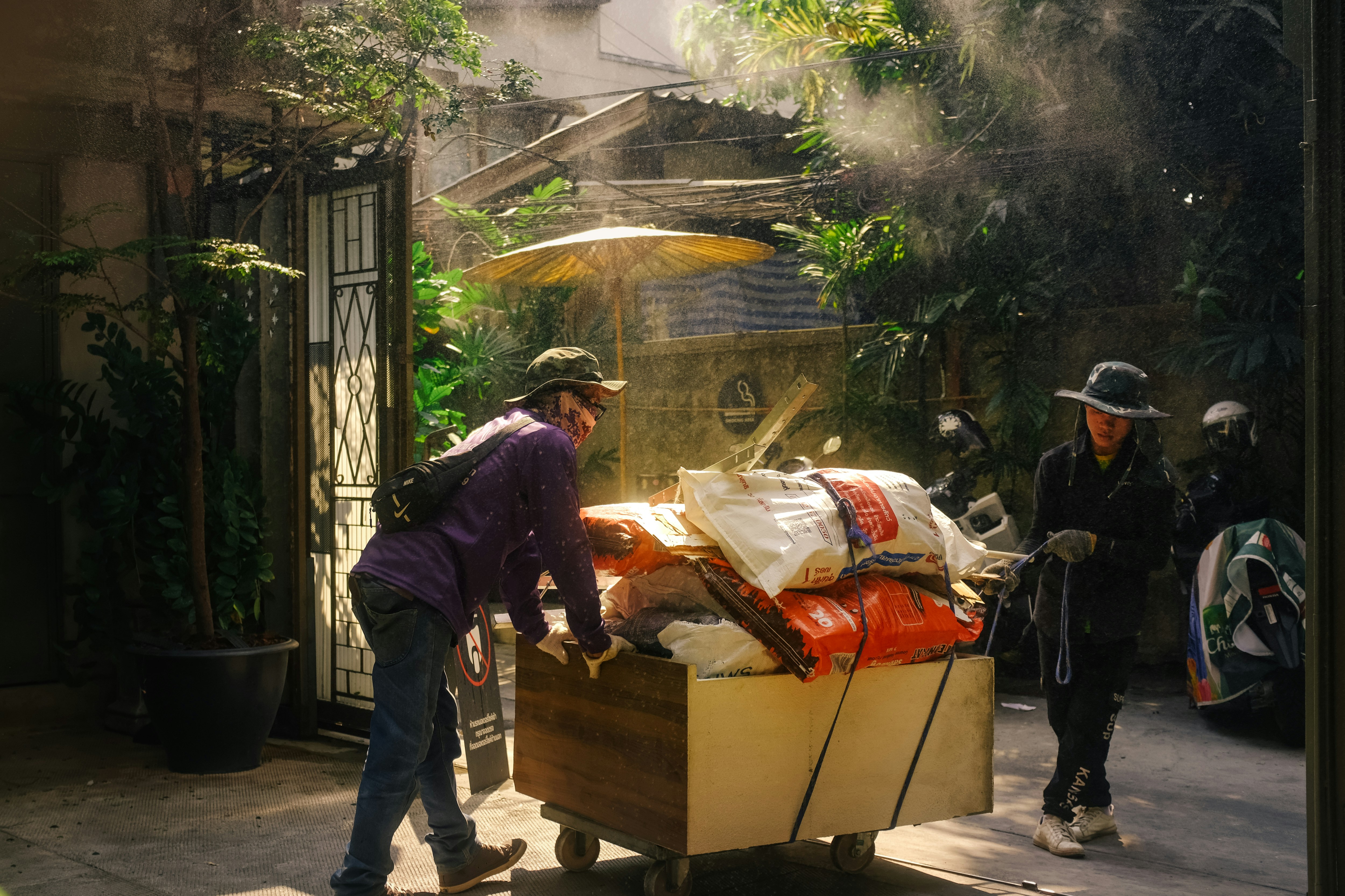 People moving large bundles on a cart