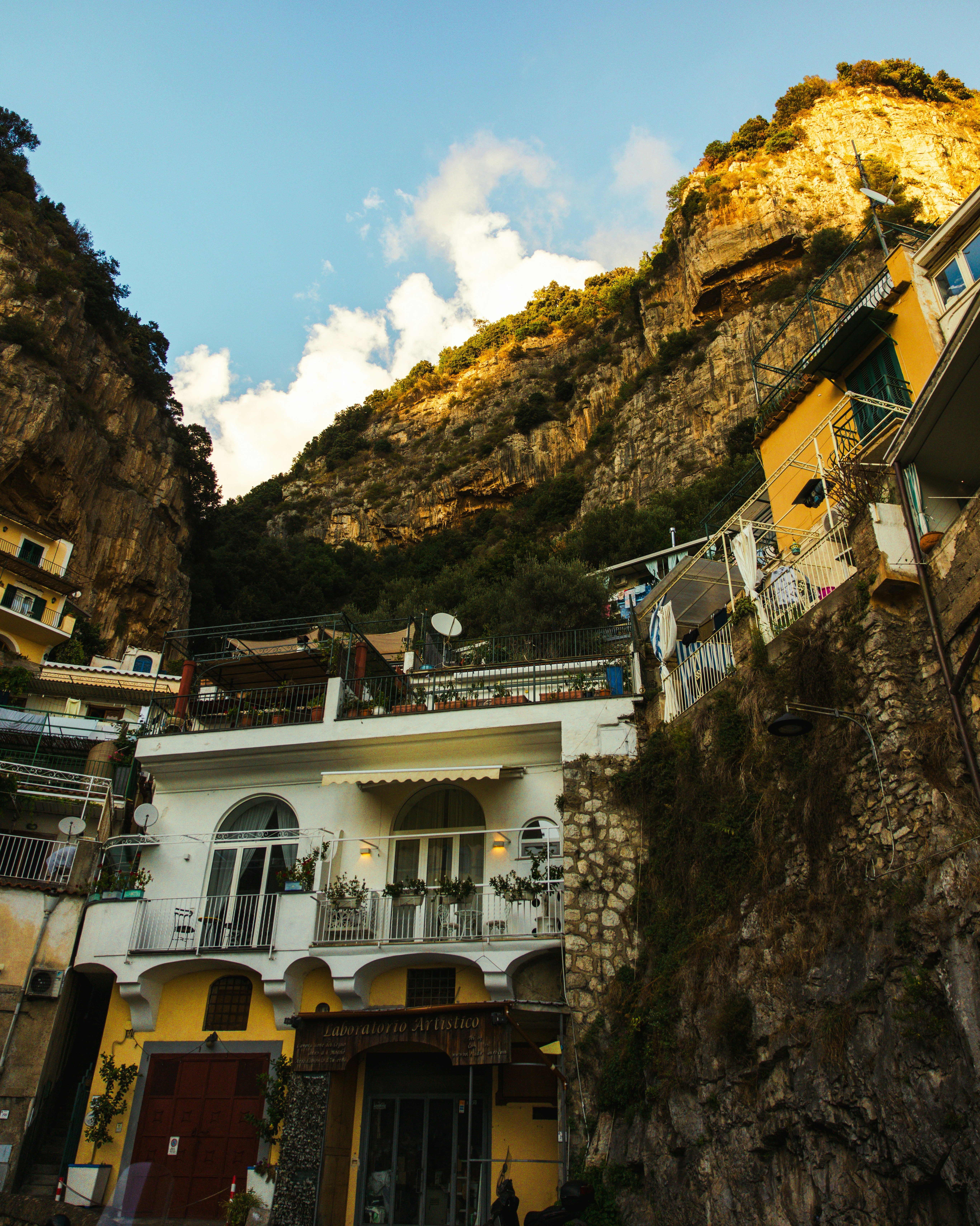 Buildings nestled into a steep, sunlit cliffside.
