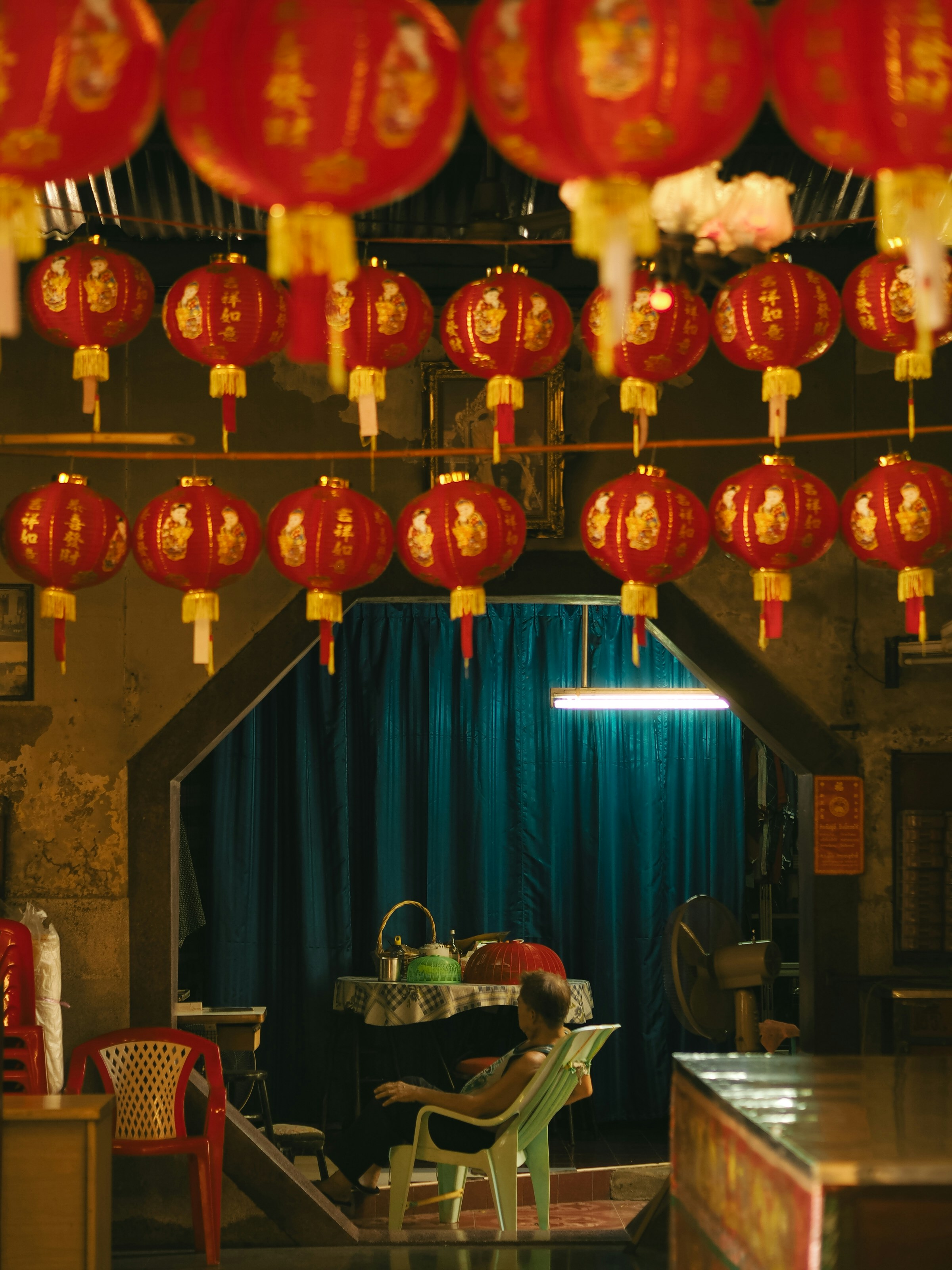 Rows of red lanterns hang above a seated person.