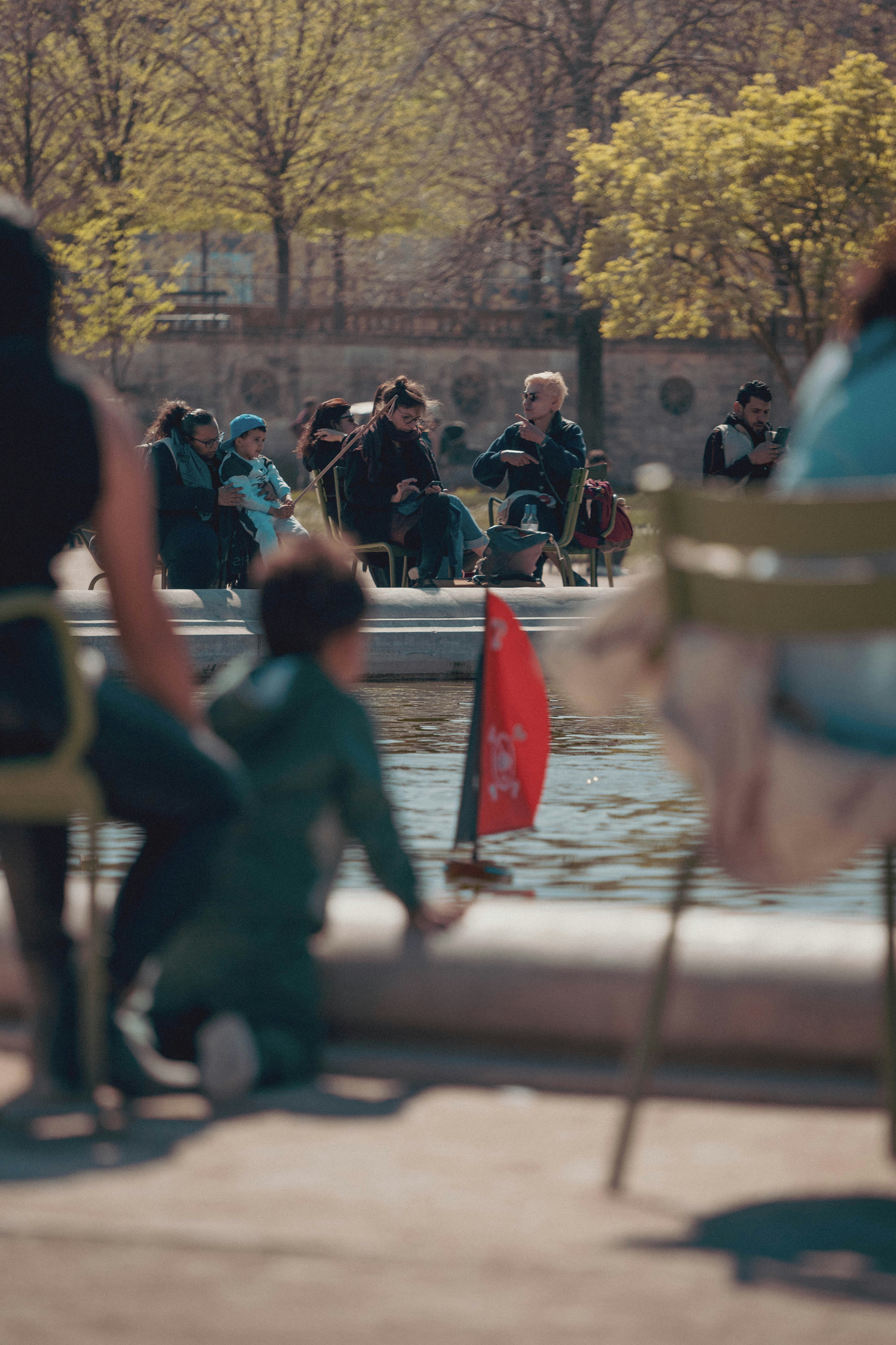 Children playing with a toy boat near a fountain.