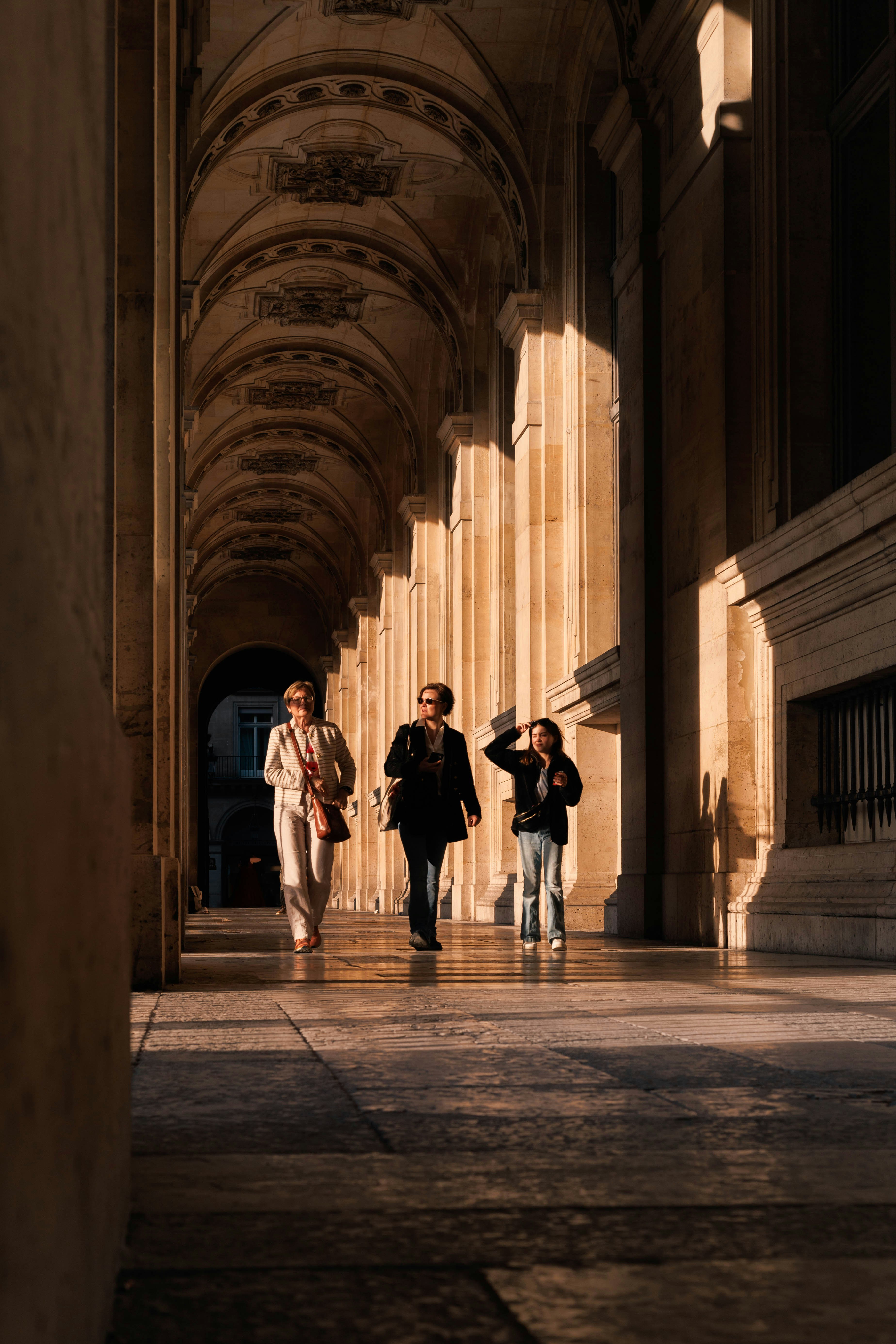 People walking through a sunlit stone archway