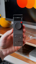 Hand holding a modern digital controller with buttons.