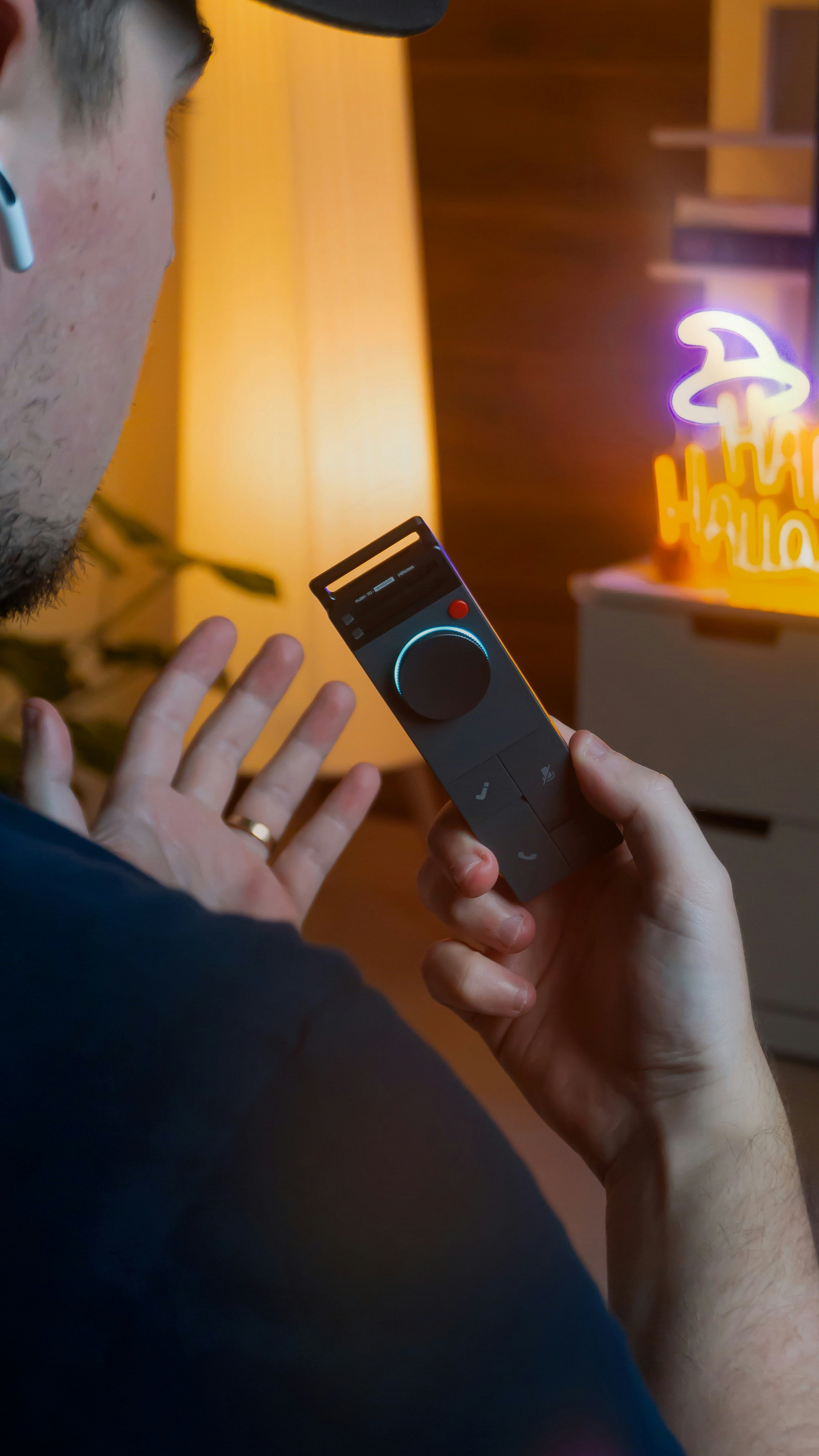 Hombre sosteniendo un control remoto con un letrero de neón