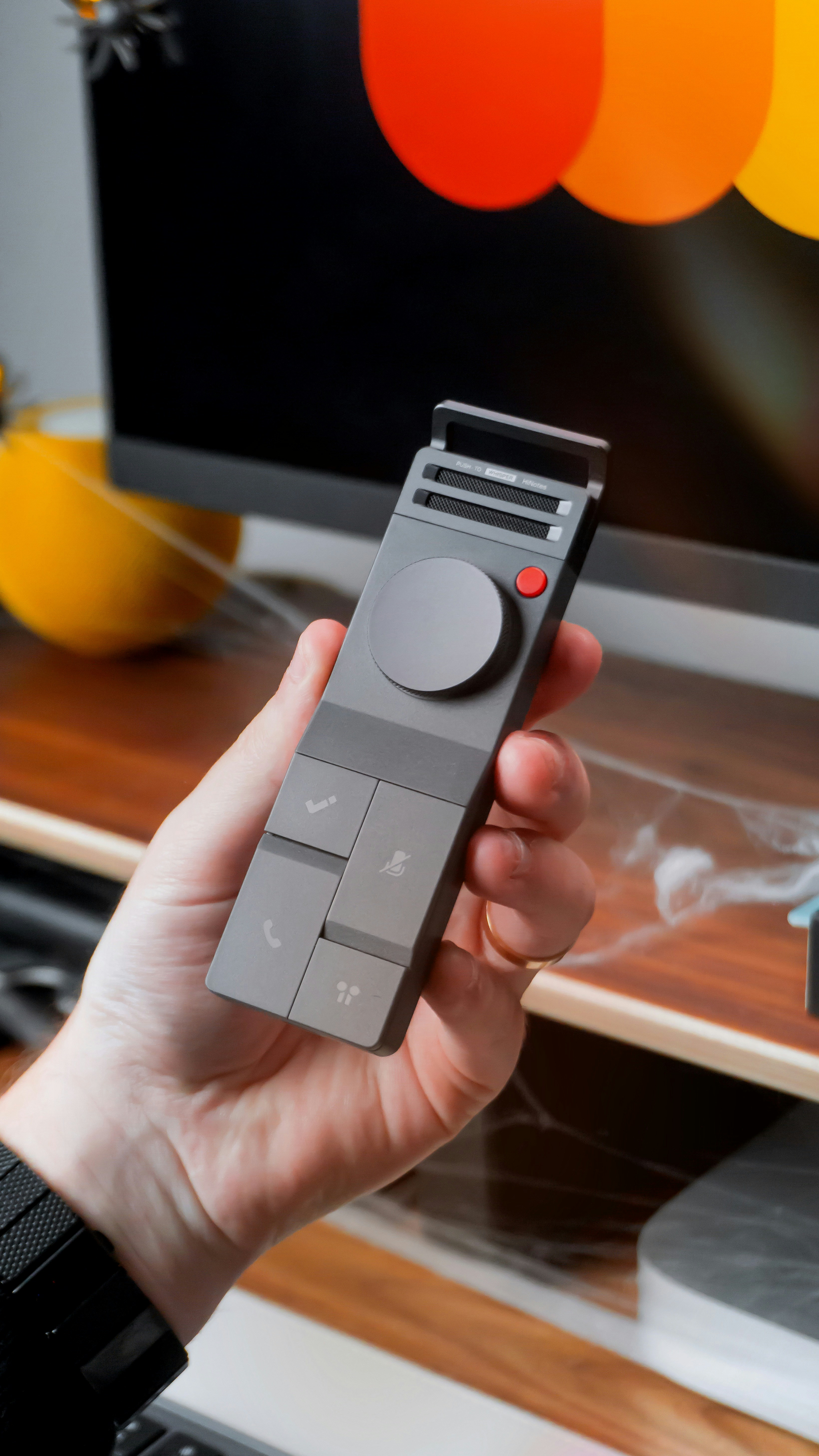 Hand holding a gray remote control with buttons.