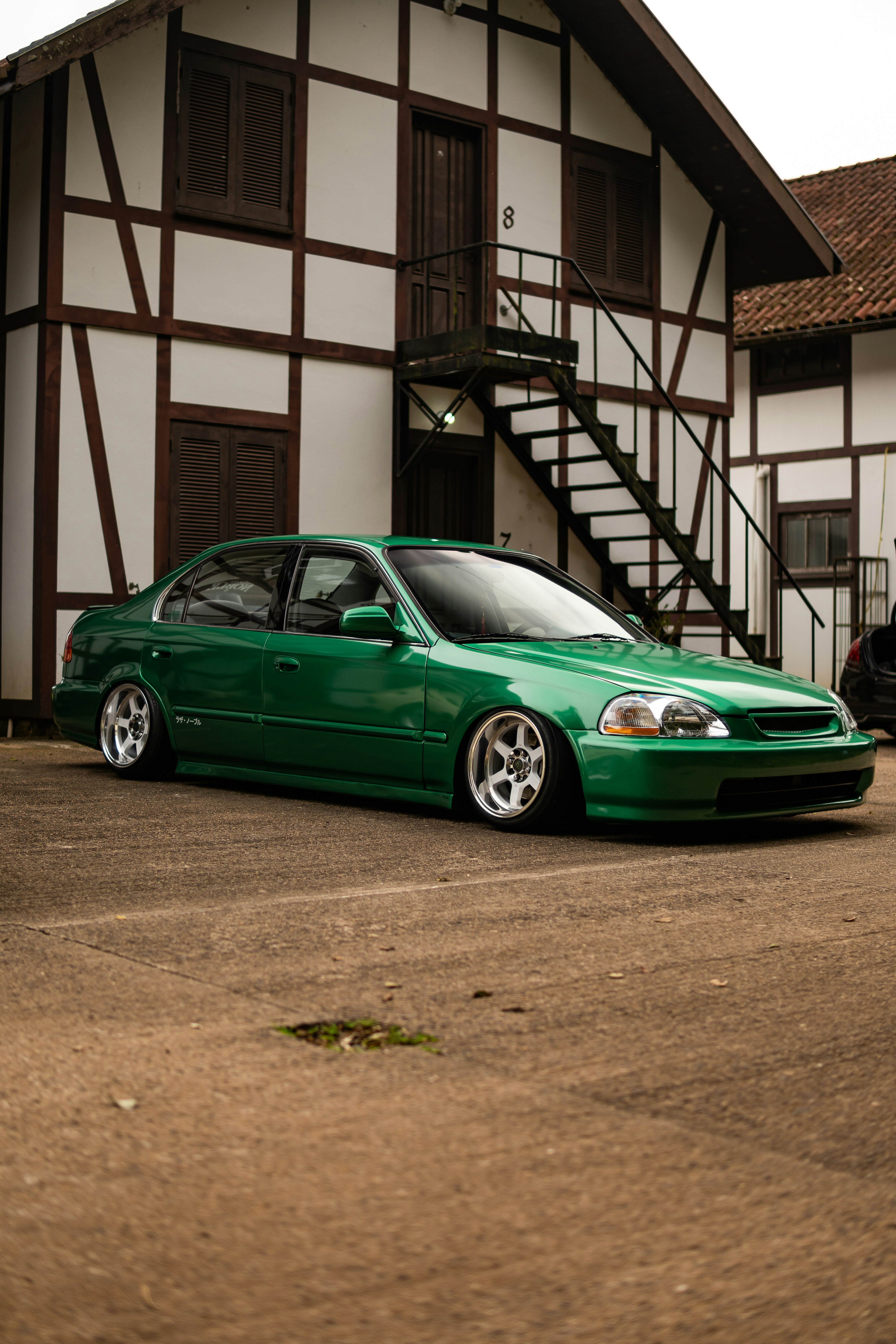 A lowered green sedan parked in front of a building