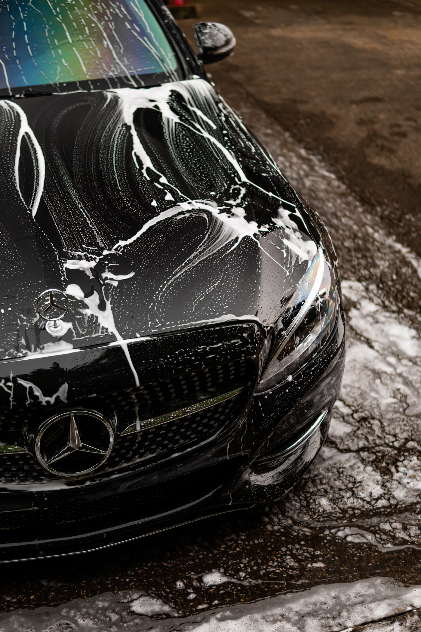 Foam on the glossy hood of a black luxury car