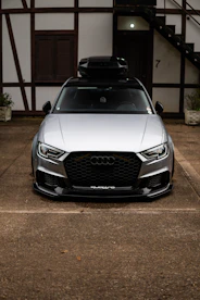 Silver audi with roof box parked outside building entrance