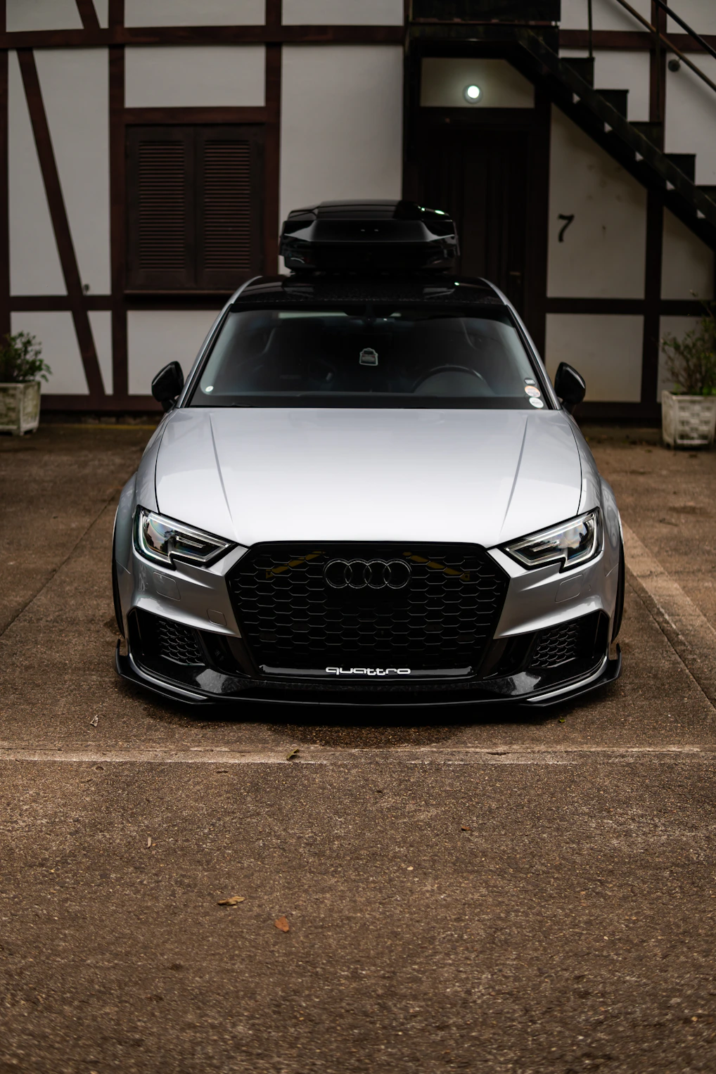 Silver audi with roof box parked outside building entrance