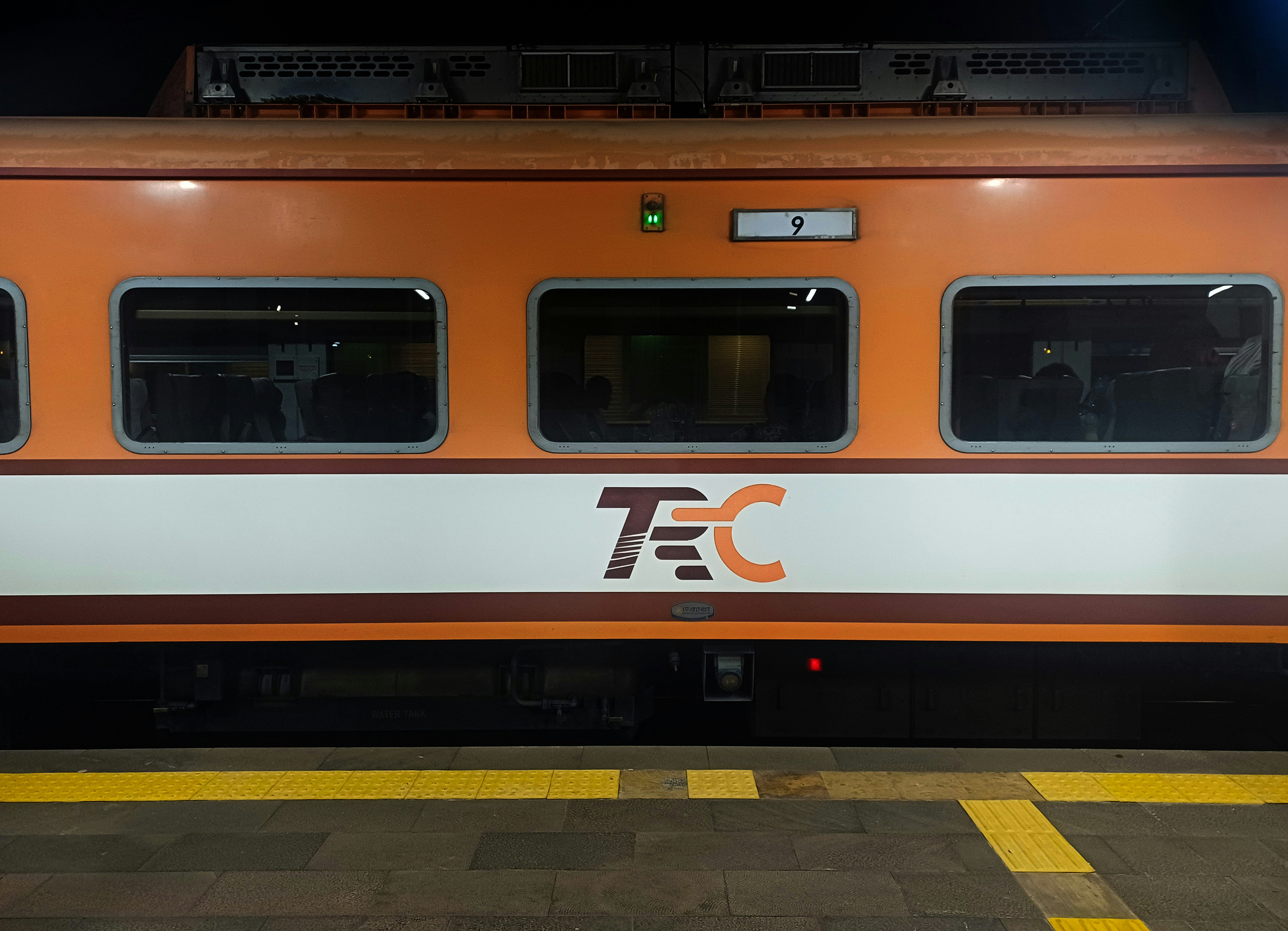 Orange and white train with tec logo at station