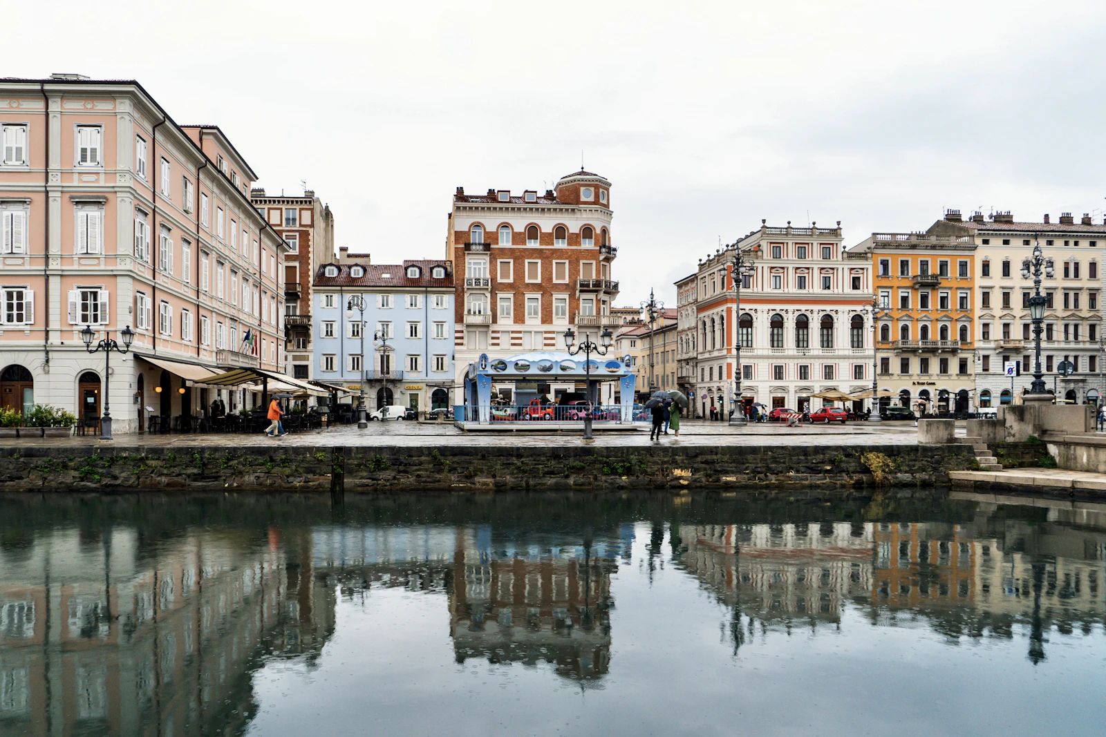 Buildings reflected in a calm canal on an overcast day