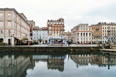 Buildings reflected in a calm canal on an overcast day