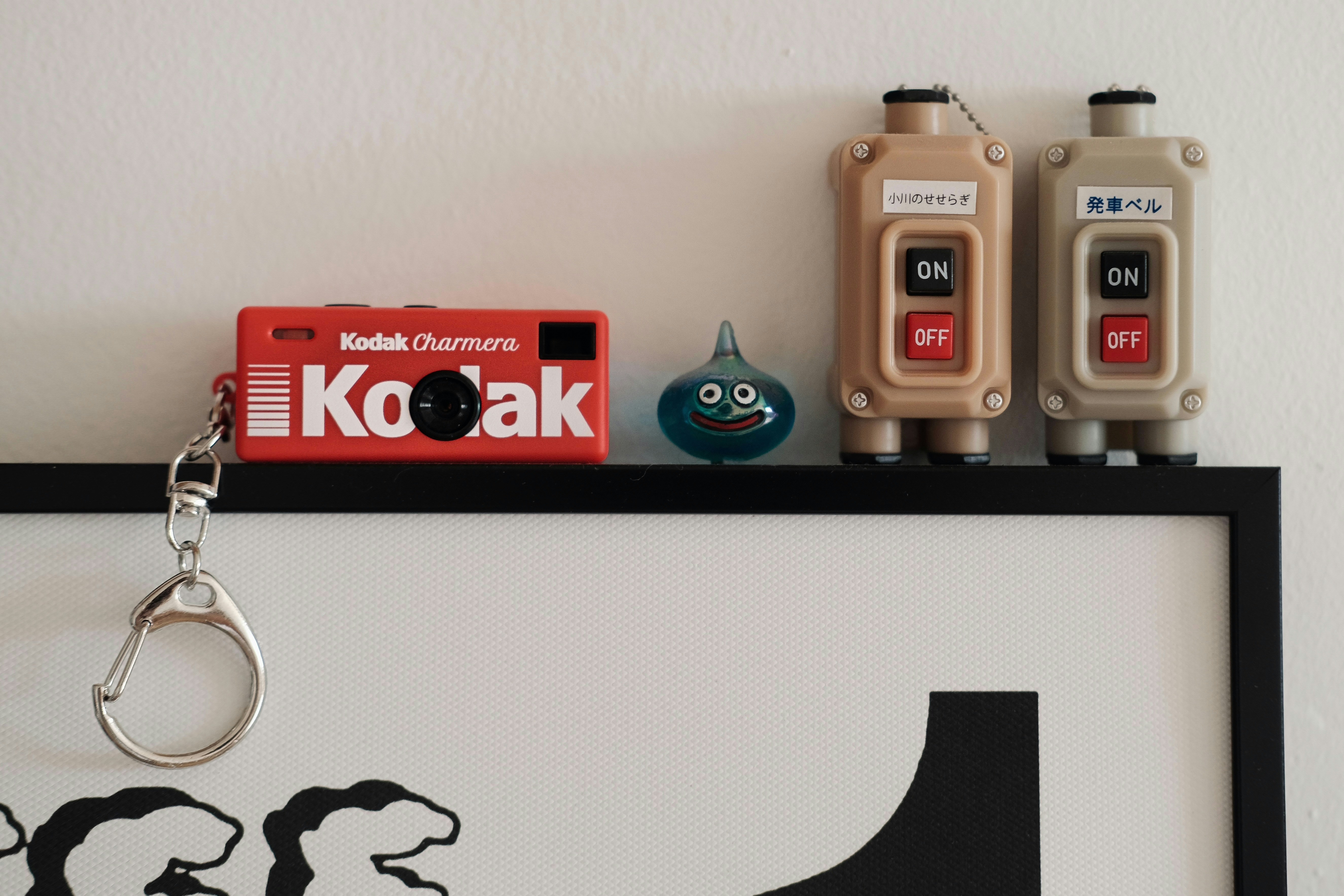 Kodak camera, slime figure, and two beige devices on shelf.