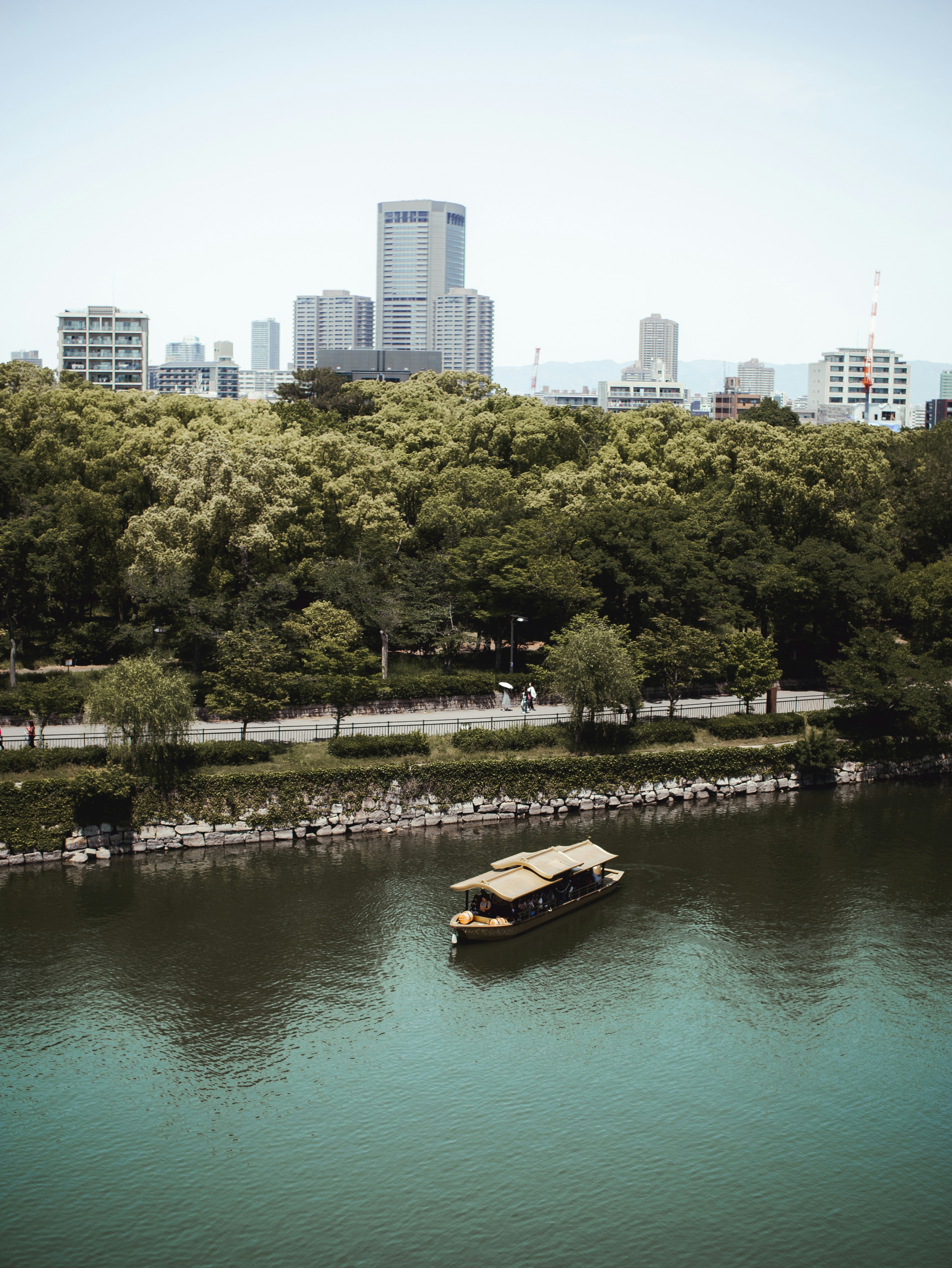 Boat on river with city skyline behind trees
