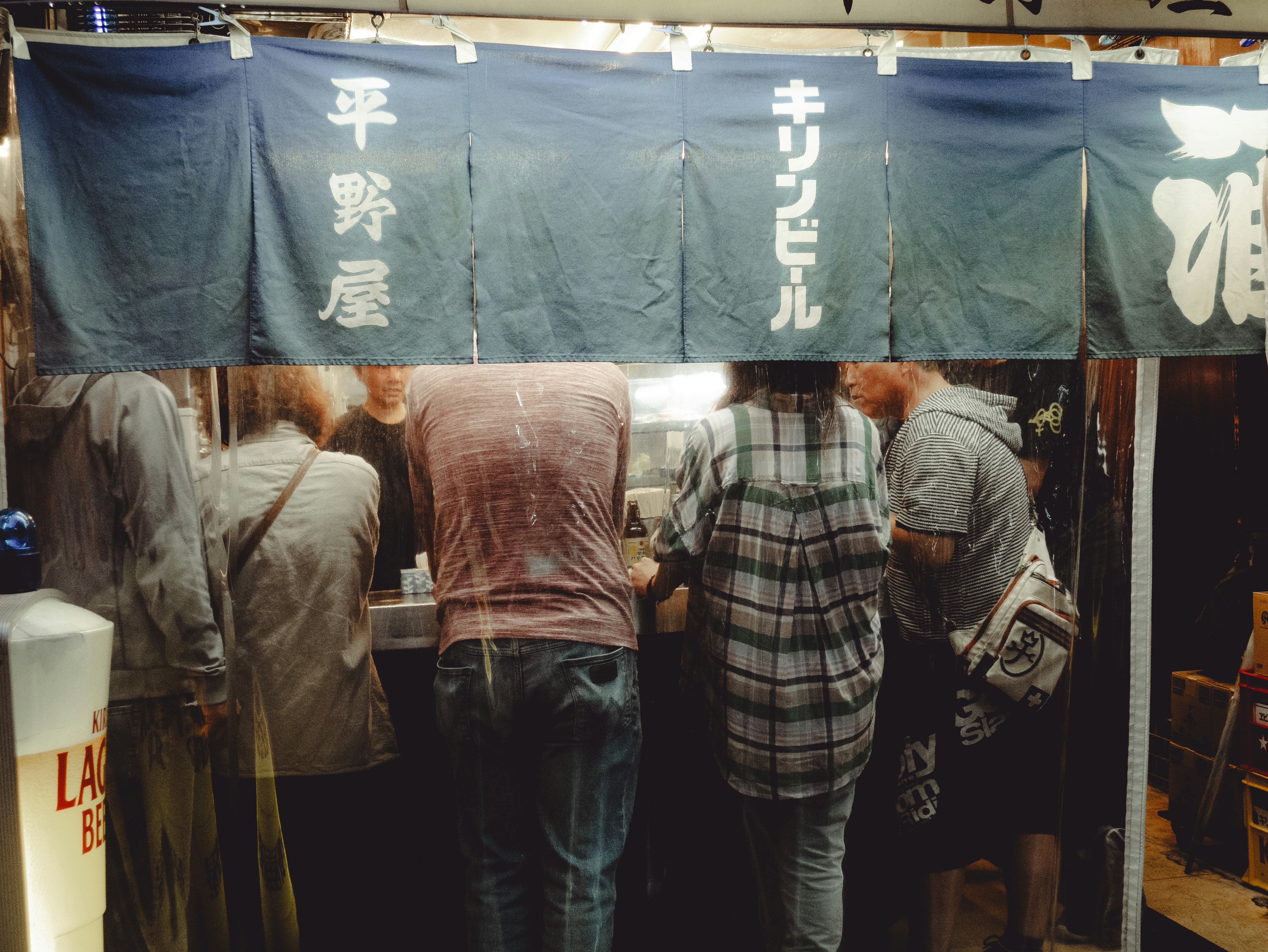 People gathered at a japanese food stall at night.