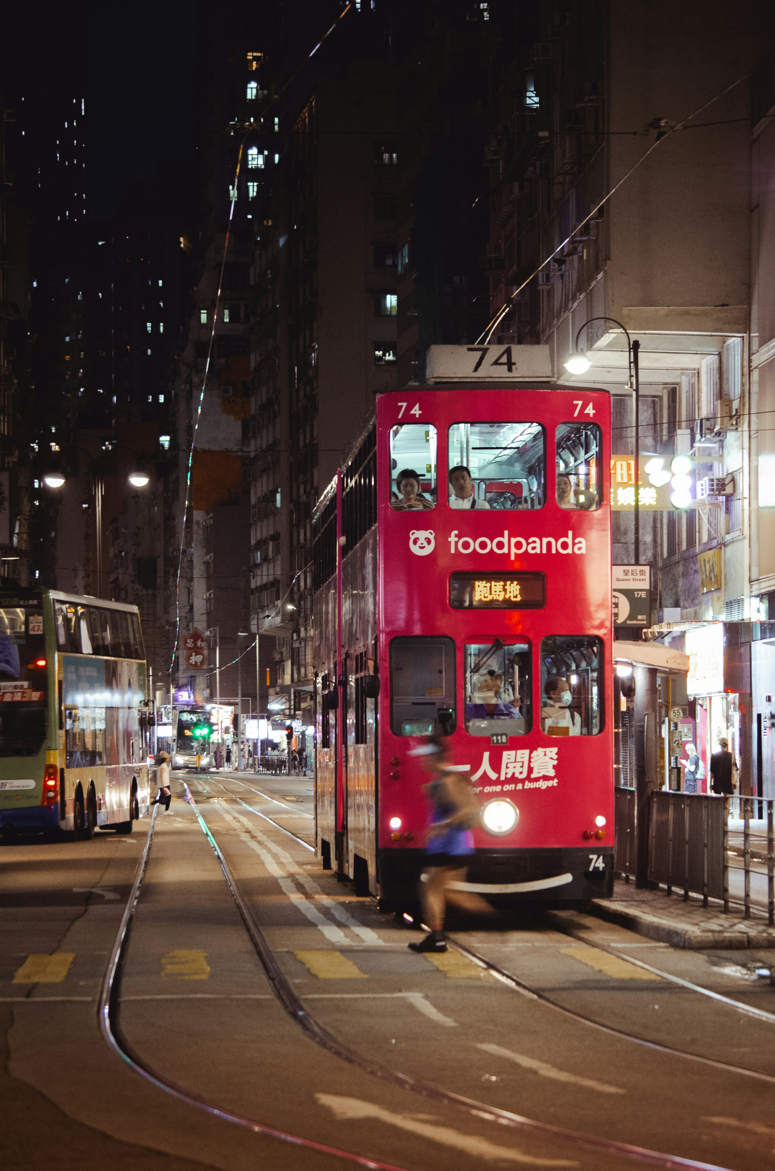 Red tram moving through a city street at night