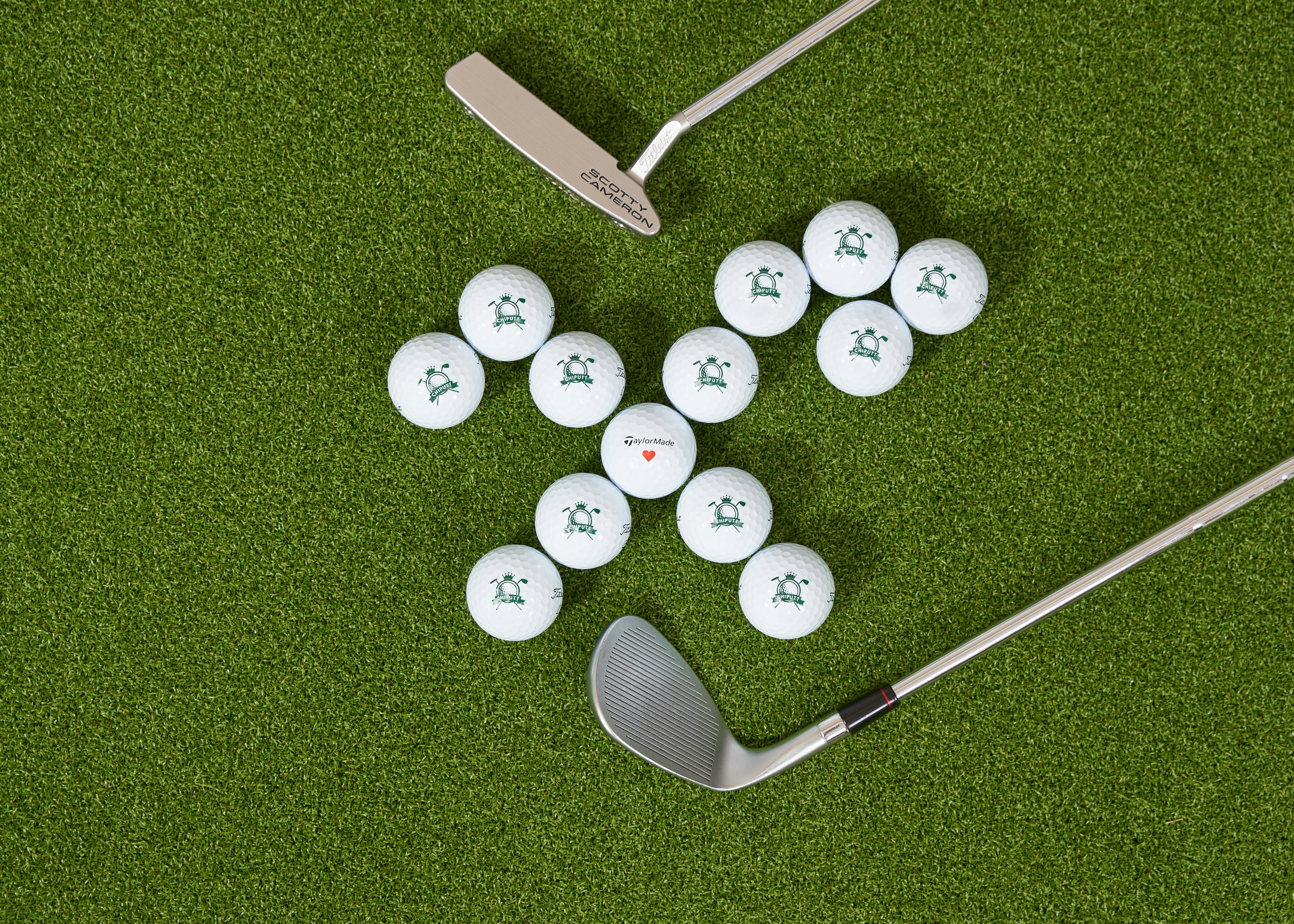 Golf balls and clubs arranged on green turf