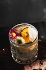A refreshing cocktail garnished with flowers and citrus.