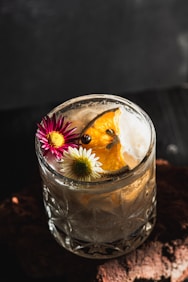 A refreshing cocktail garnished with flowers and citrus.