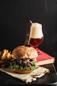 Juicy burger with fries and a glass of beer.