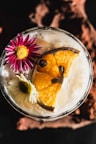 Cocktail garnished with orange slice and flowers