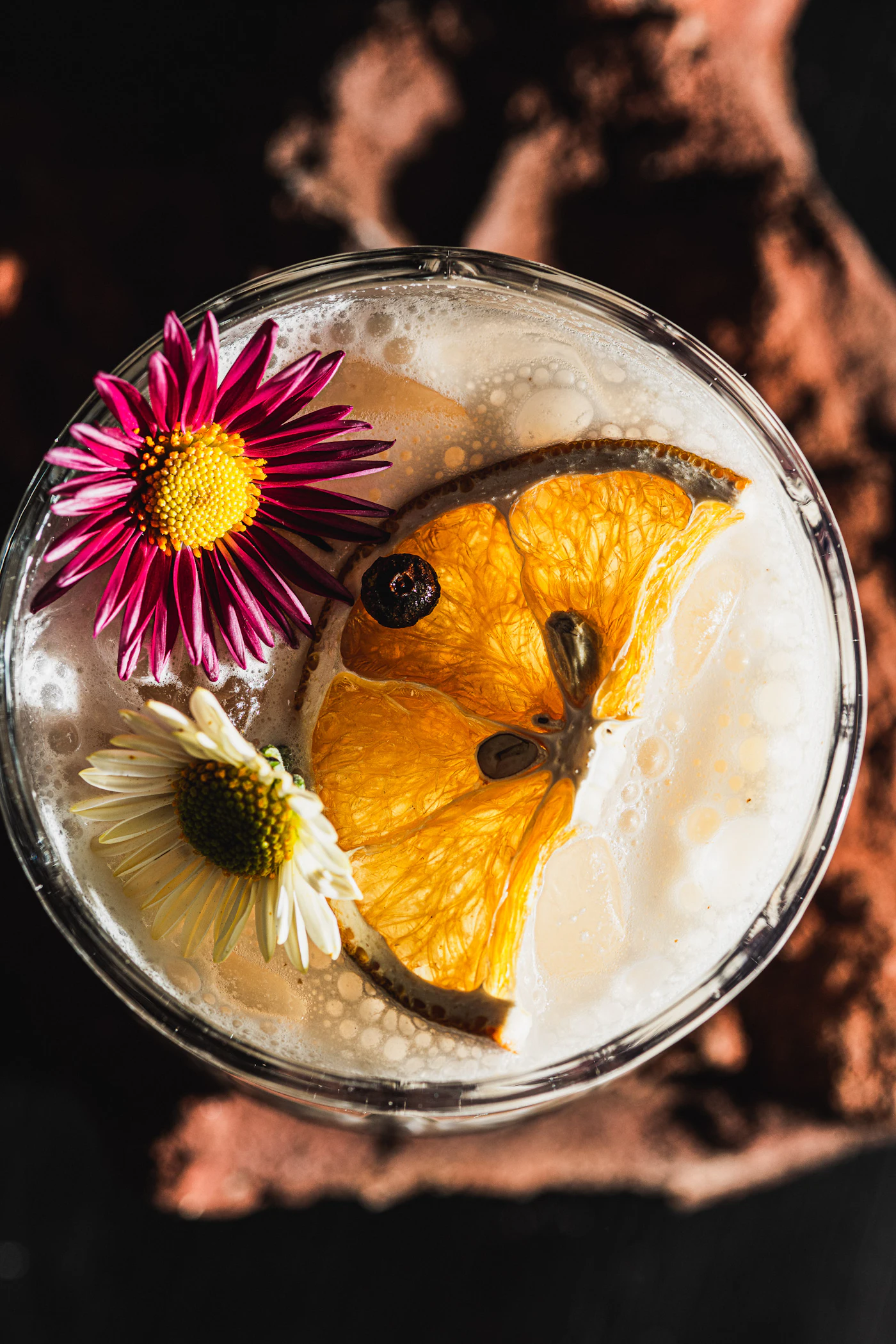 Cocktail garni d’une tranche d’orange déshydratée et de fleurs