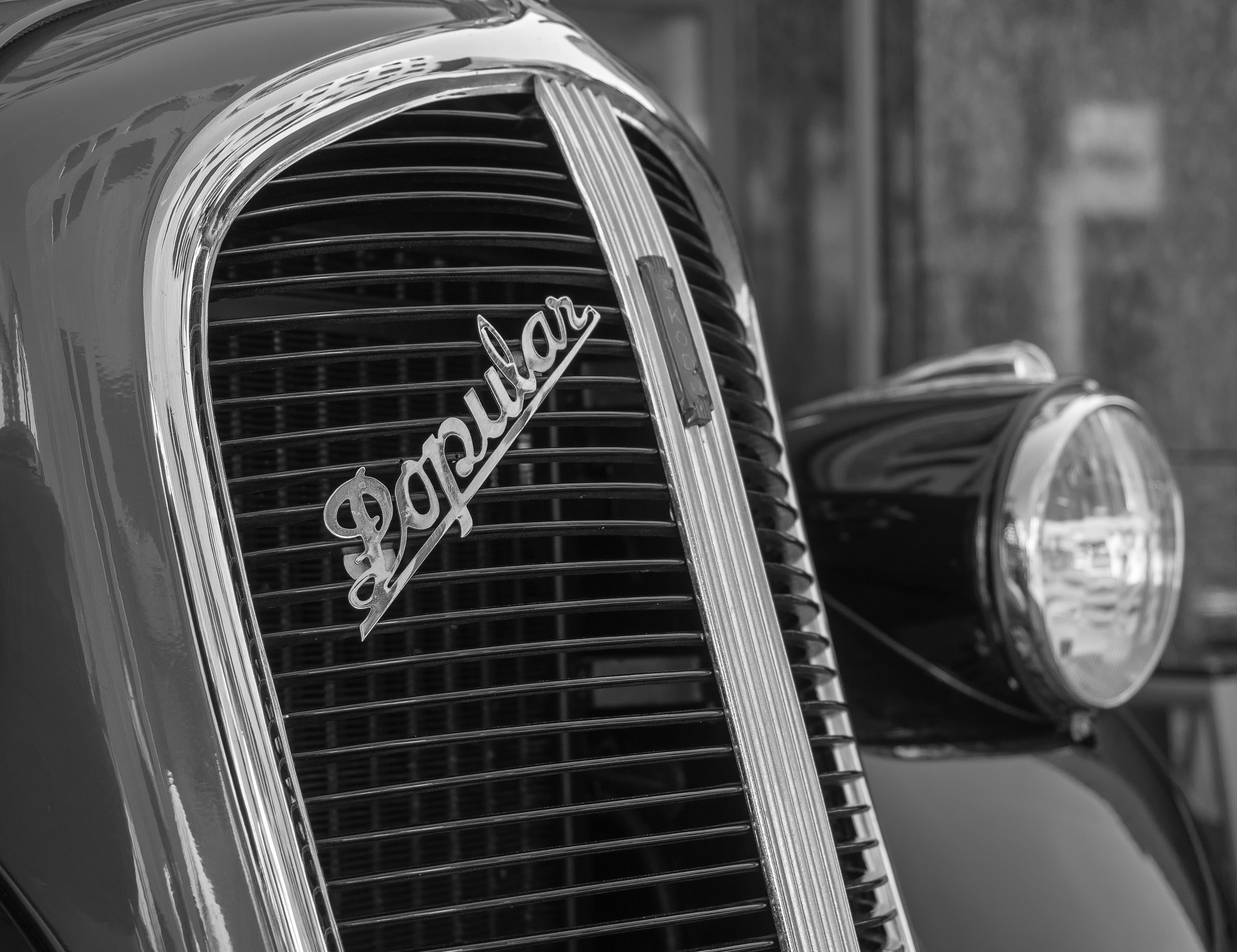 Close-up of a vintage car grille with 'popular' emblem.