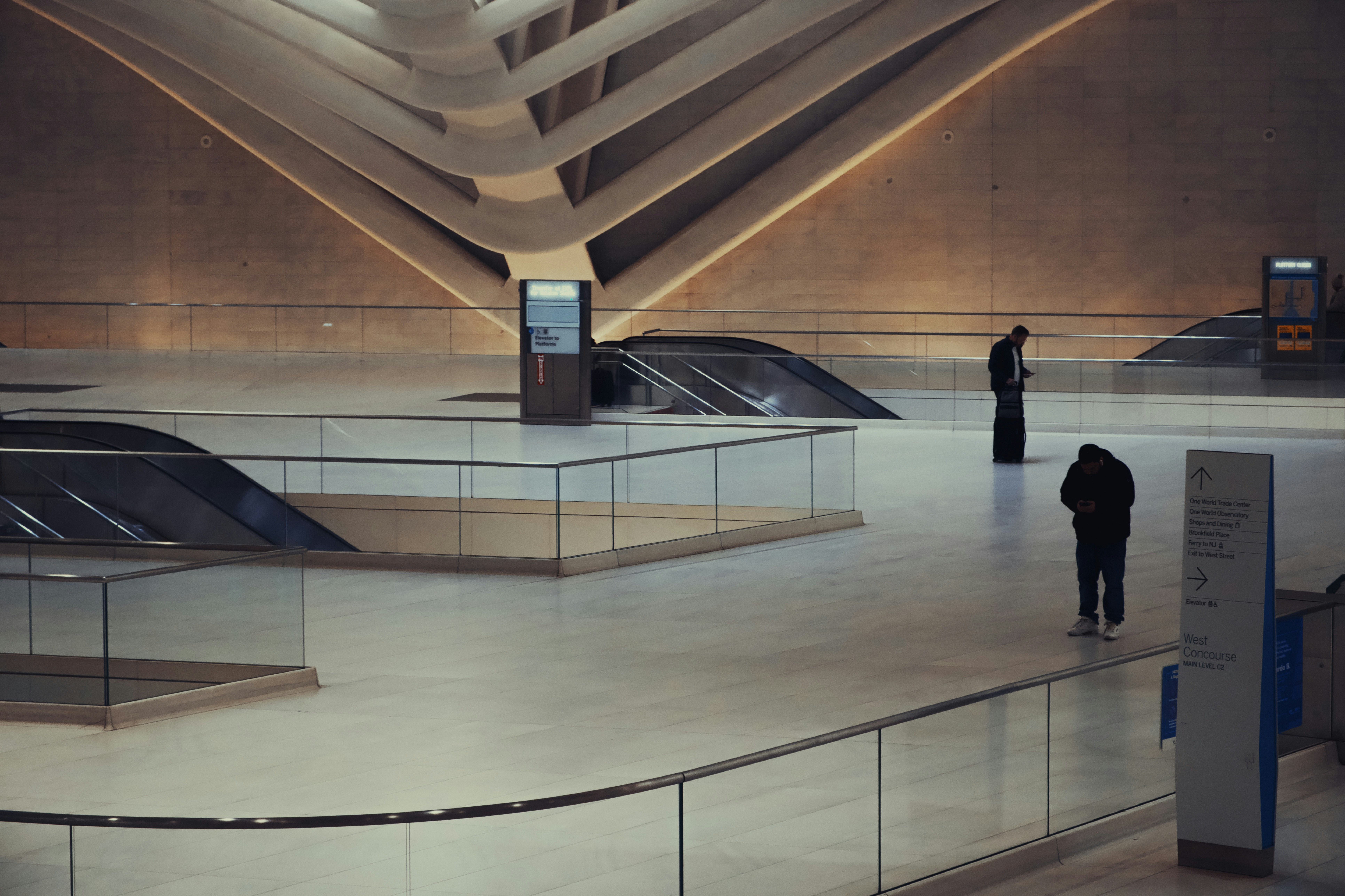 Modern architectural interior with escalators and people.