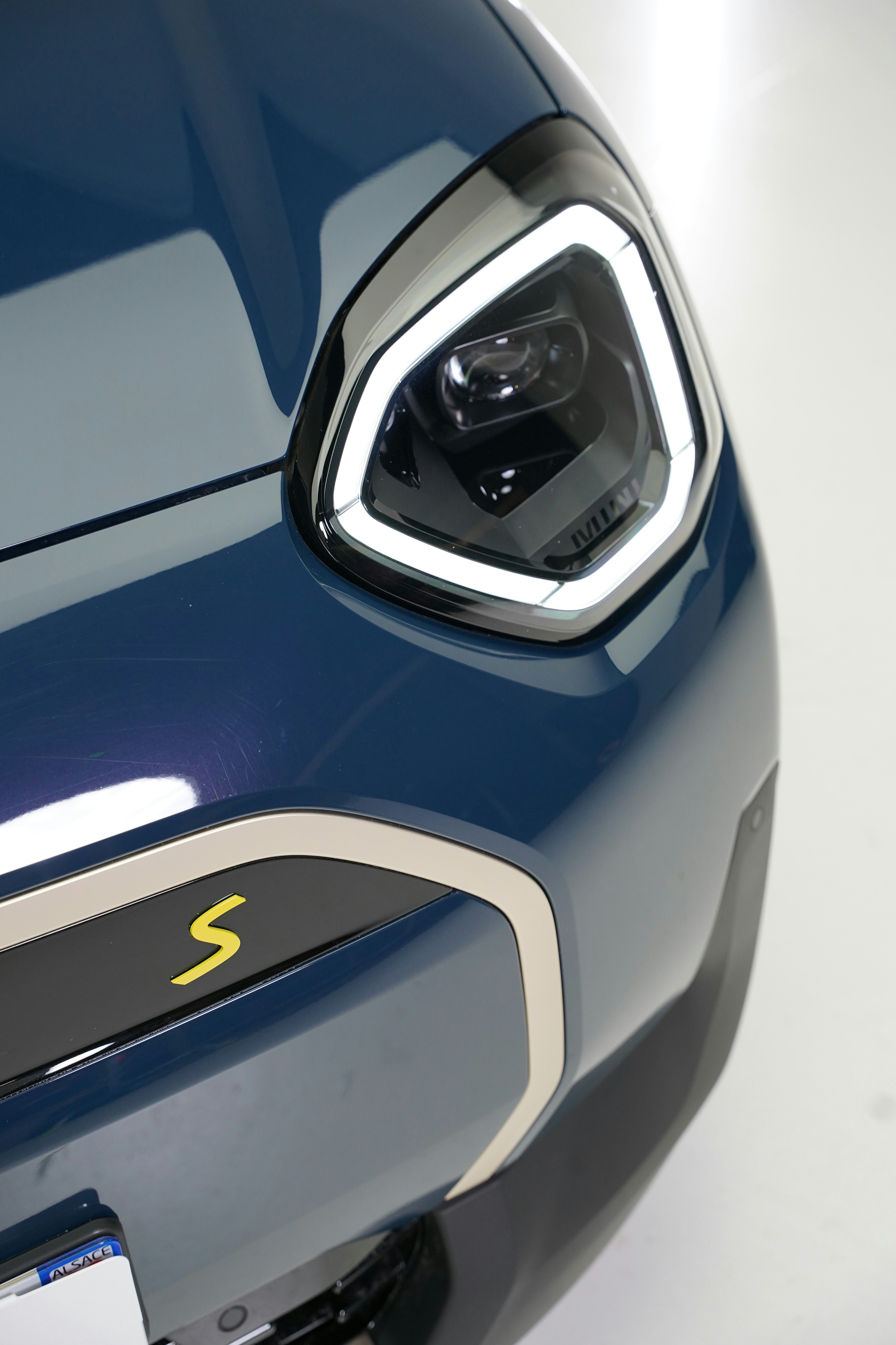 Close-up of a modern blue car headlight and grille.