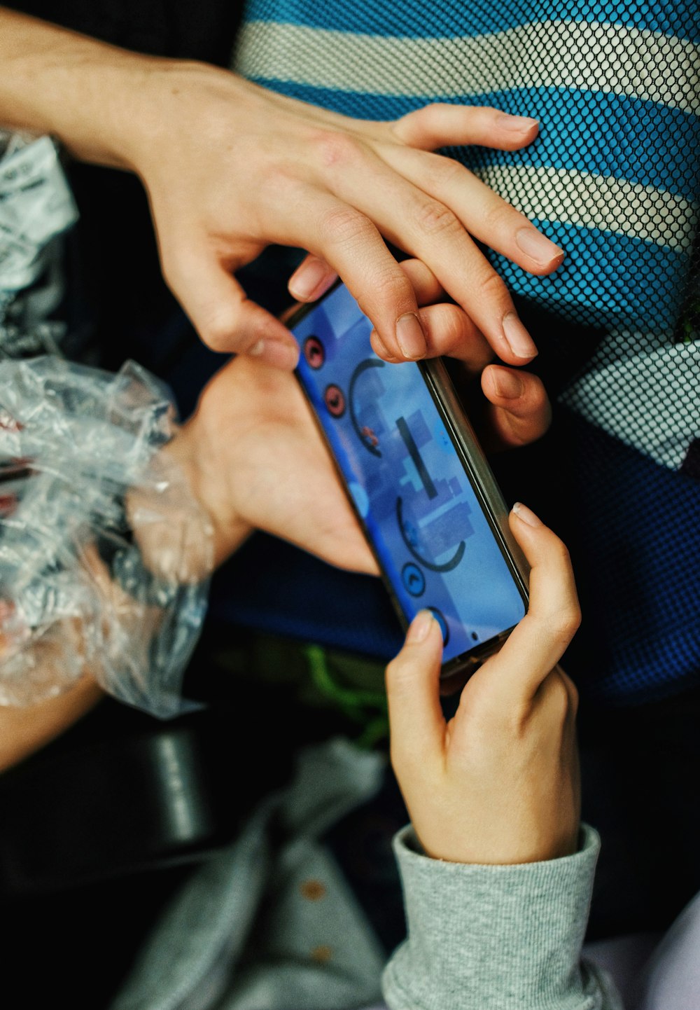 Hands holding a smartphone with a colorful game on screen, representing Star Strike Slots Casino Games as a mobile free-to-play social casino app