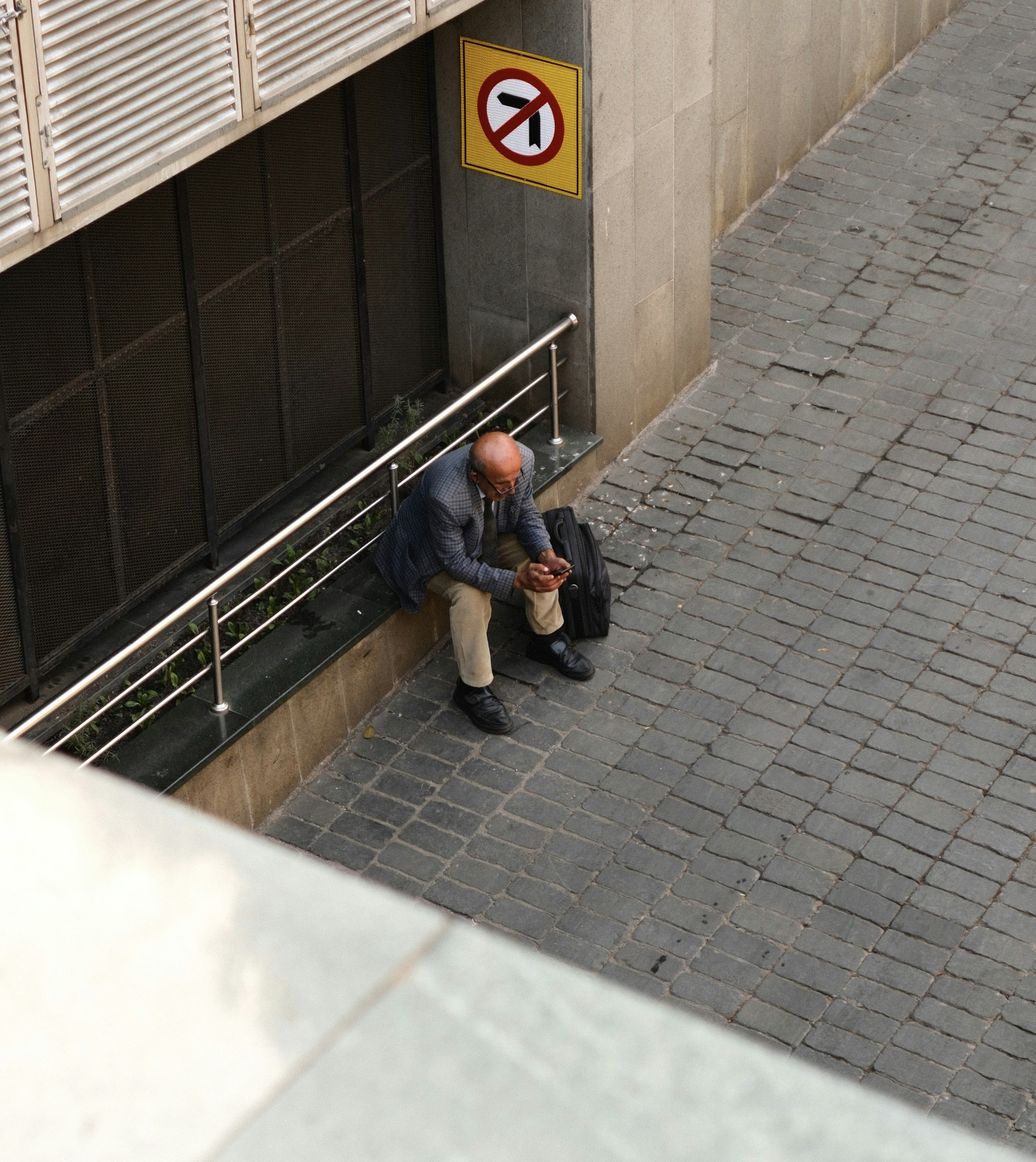 Hombre sentado en la repisa con el teléfono y el bolso.