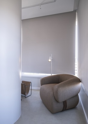 A modern armchair and floor lamp in a minimalist room.