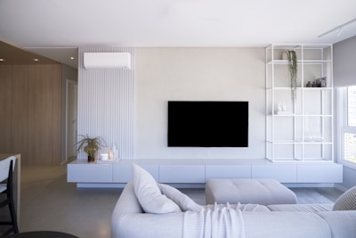 Modern living room with white furniture and large television.