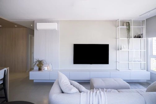 Modern living room with white furniture and large television.