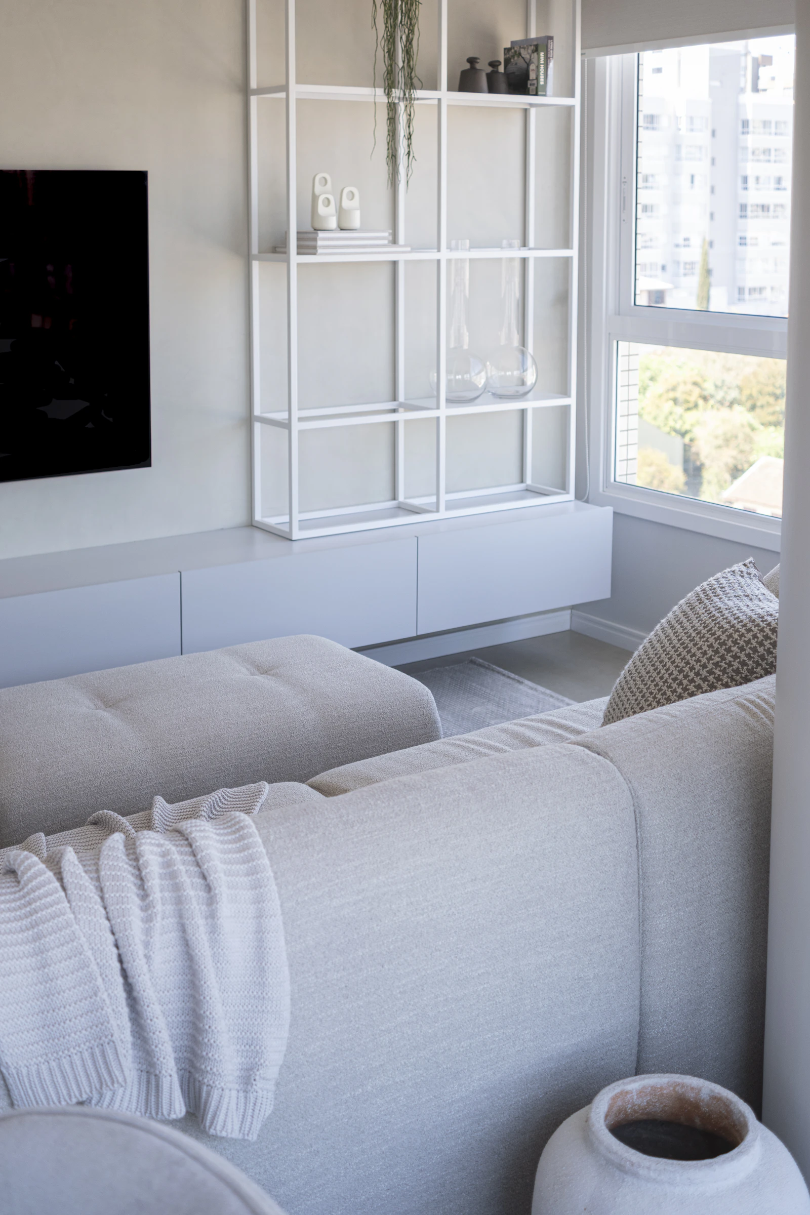 Quiet interior corner with a white shelving unit and soft fabrics.